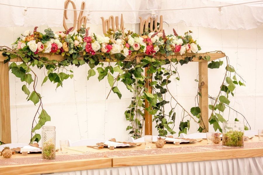 A flowery bower behind the head table at a wedding reception