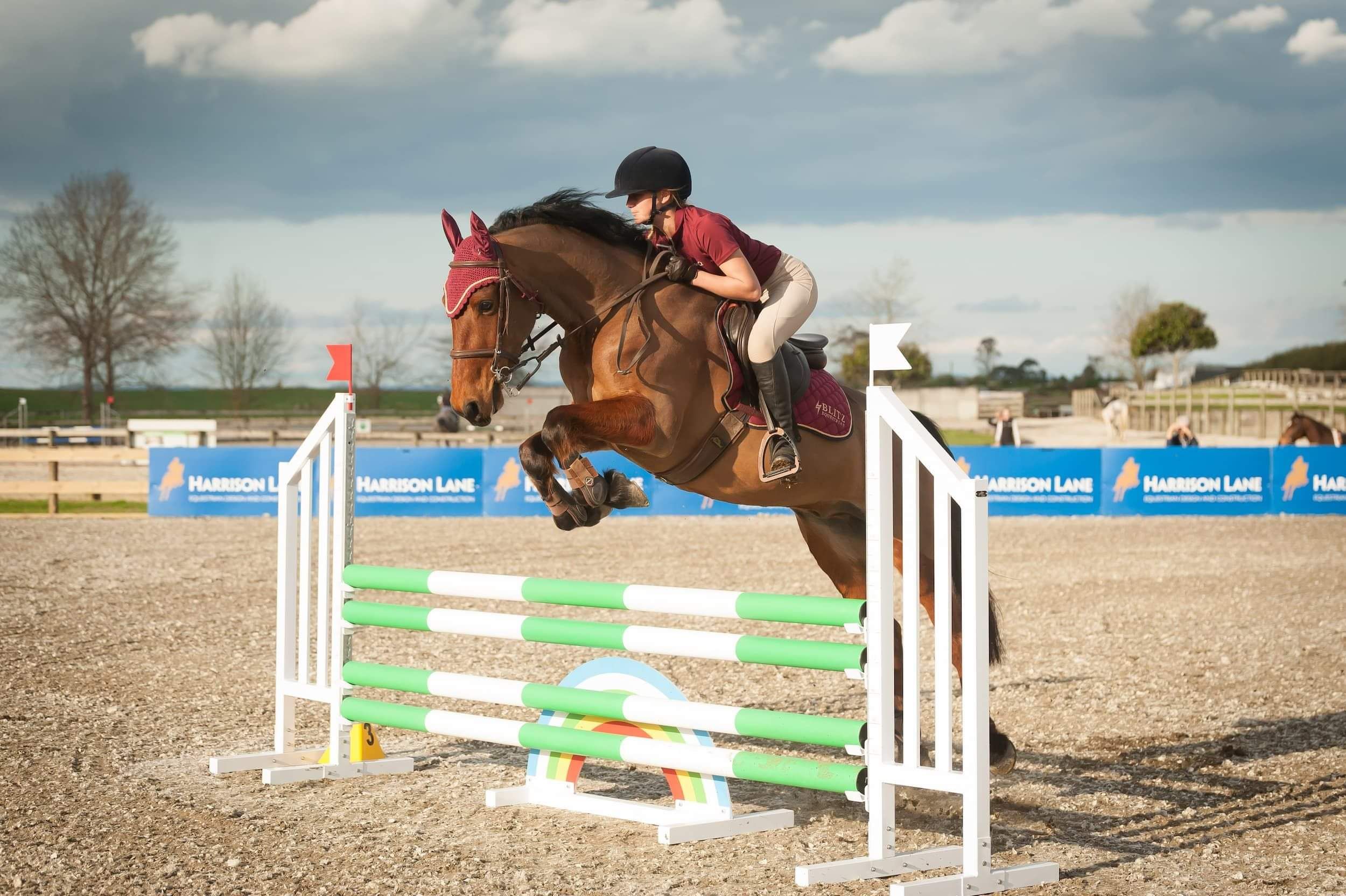 Girl and bay pony jumps vertical fence on Ebb and Flow arena