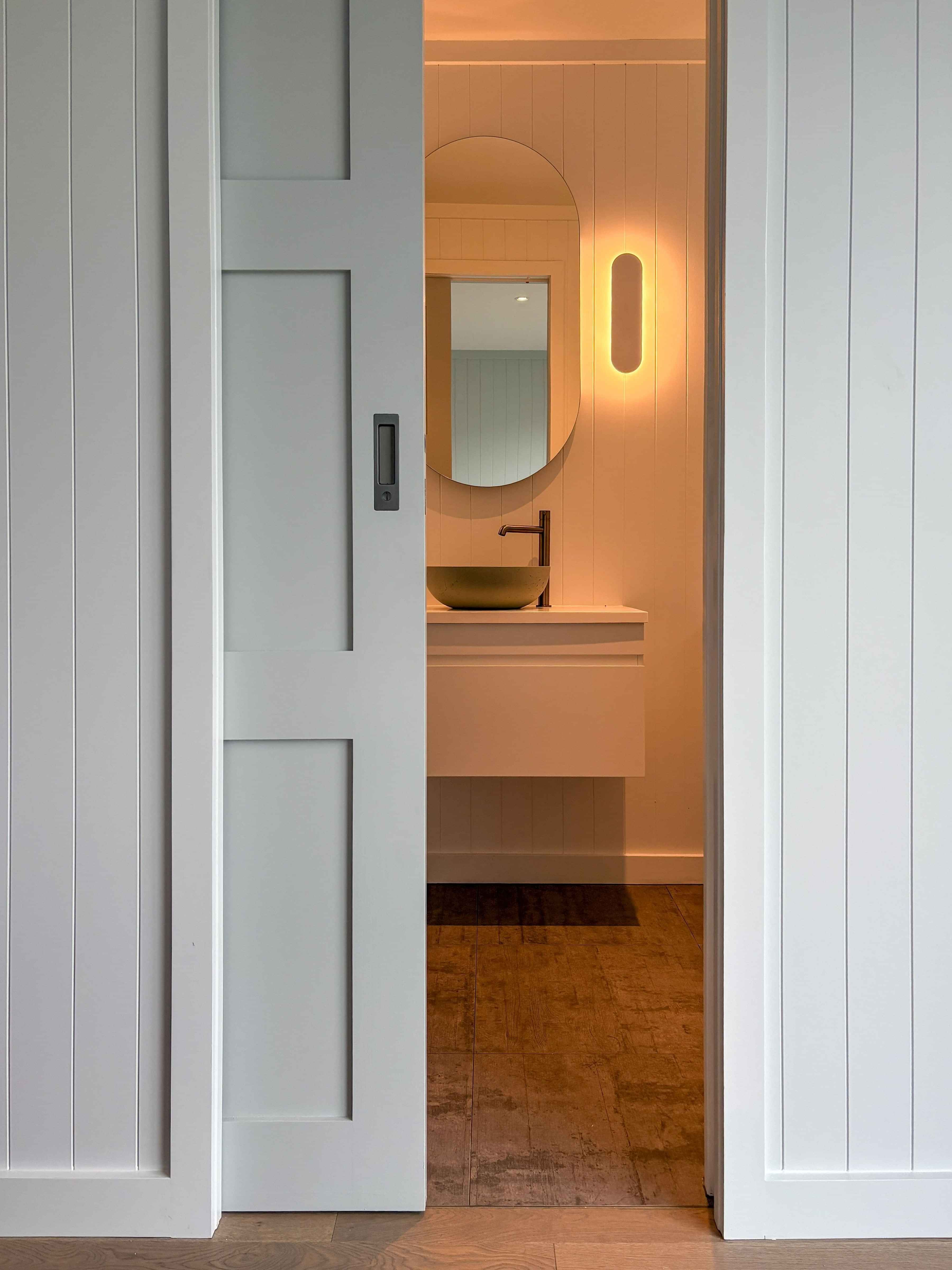 A parkwood sliding door reveals the ensuite bathroom from the bedroom