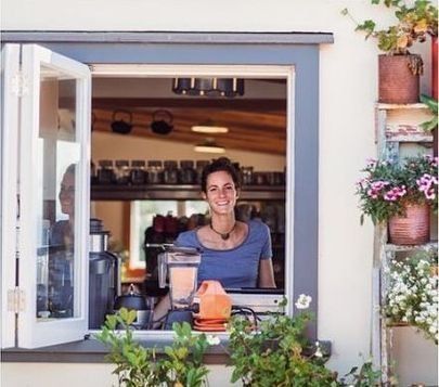 The owner of the Kuaotunu cafe, Kua Kawhe, standing at the window of the cafe