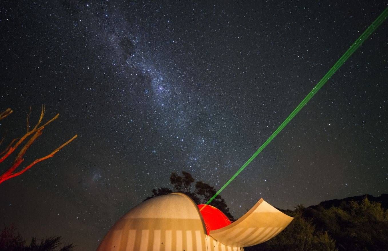 Astronomy dome at Stargazers B&B (Kuaotunu) open at night with a laser beam pointing at the night sky