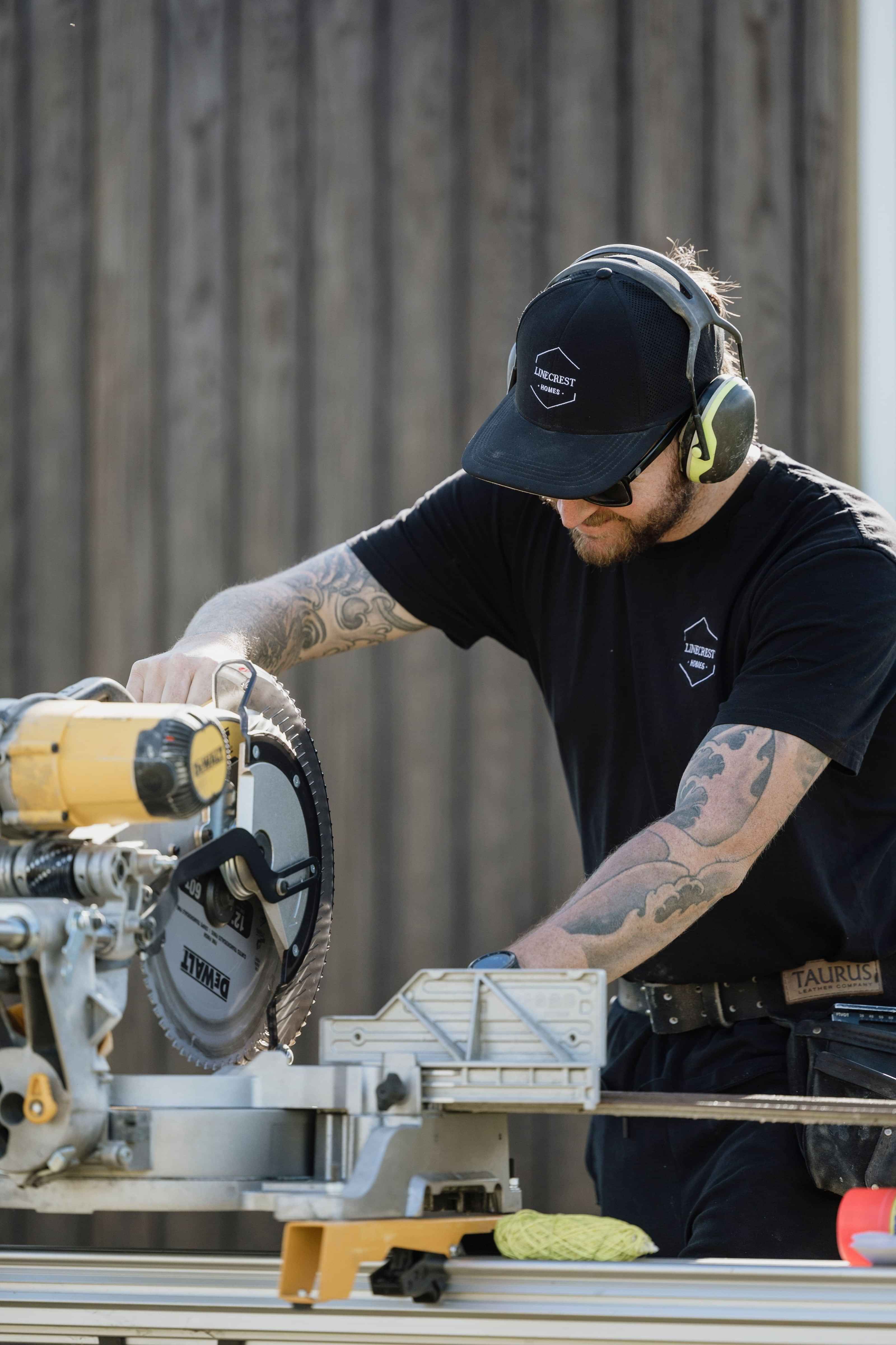 Linecrest team builder cuts timber cladding using drop saw onsite at a new home build in Matamata.