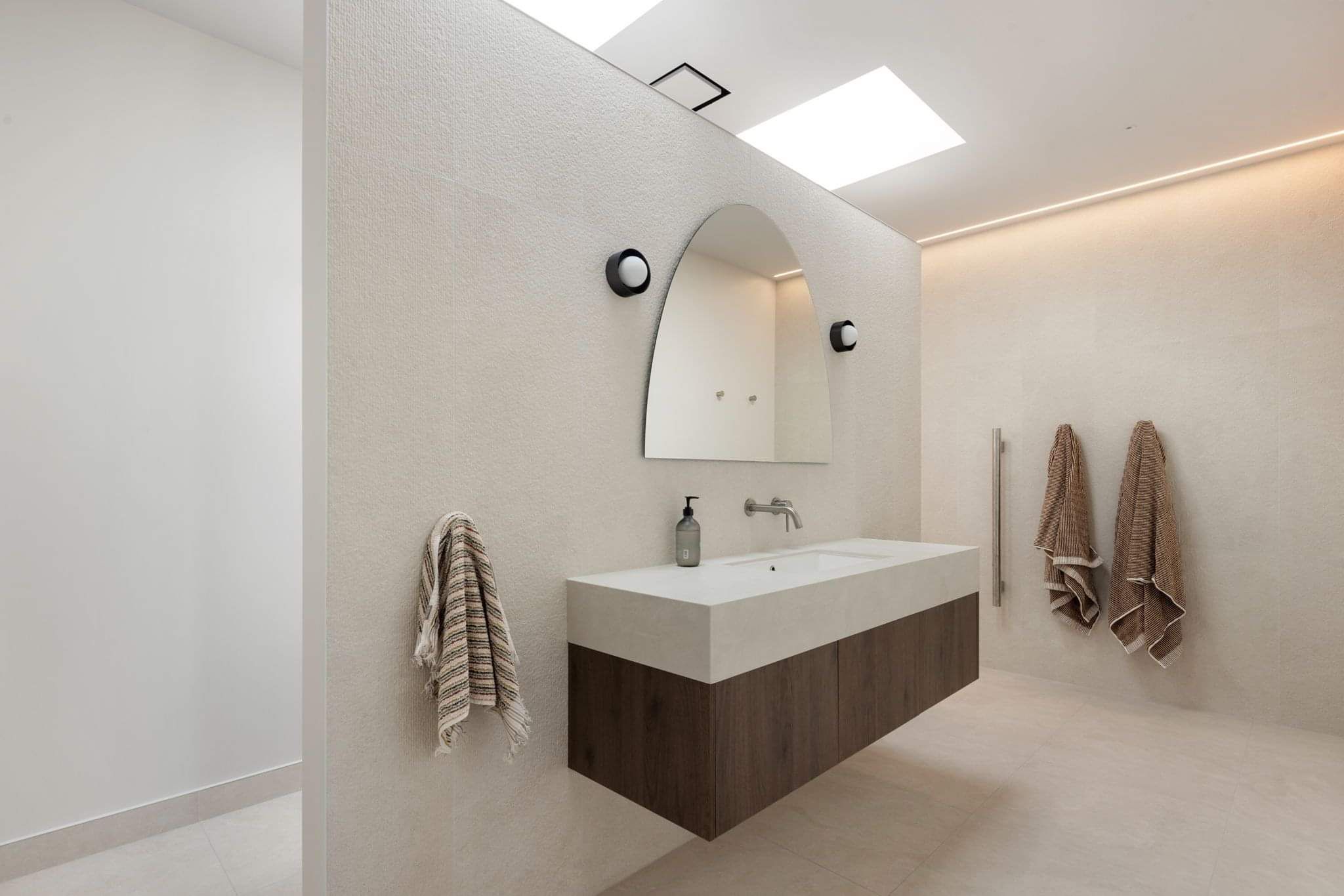 Custom-built floating wall creates a striking entrance into the bathroom showcasing architectural detail and unique design. 