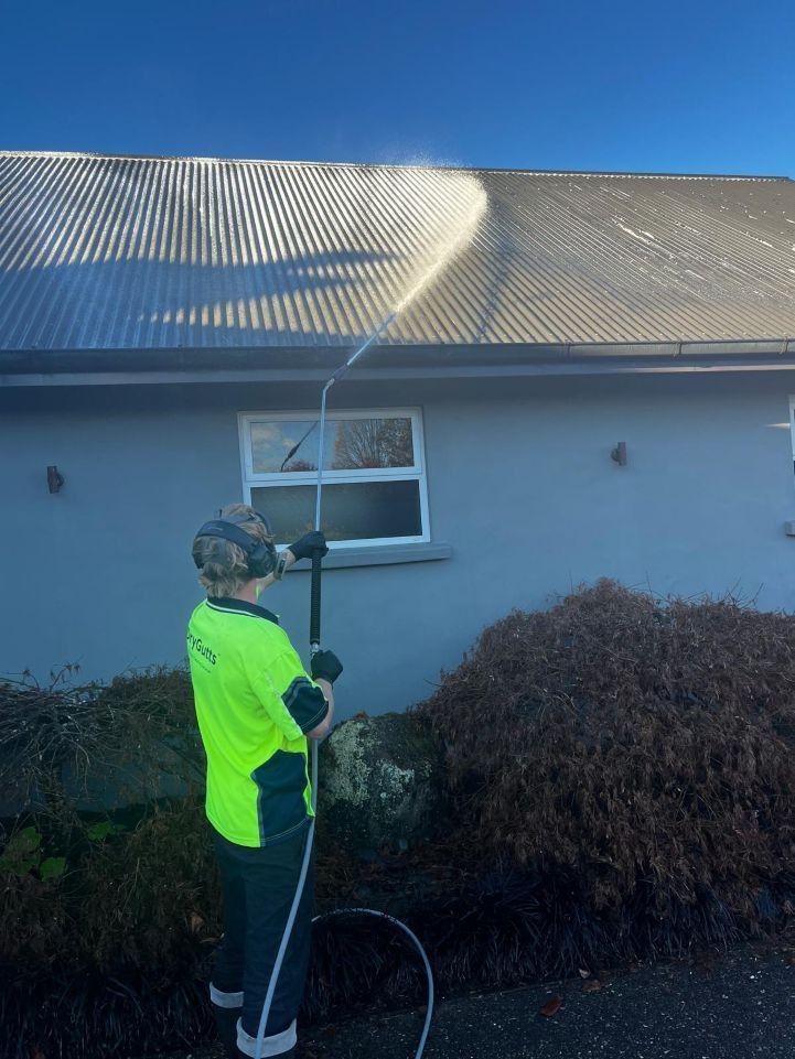Worker on roof cleaning gutters