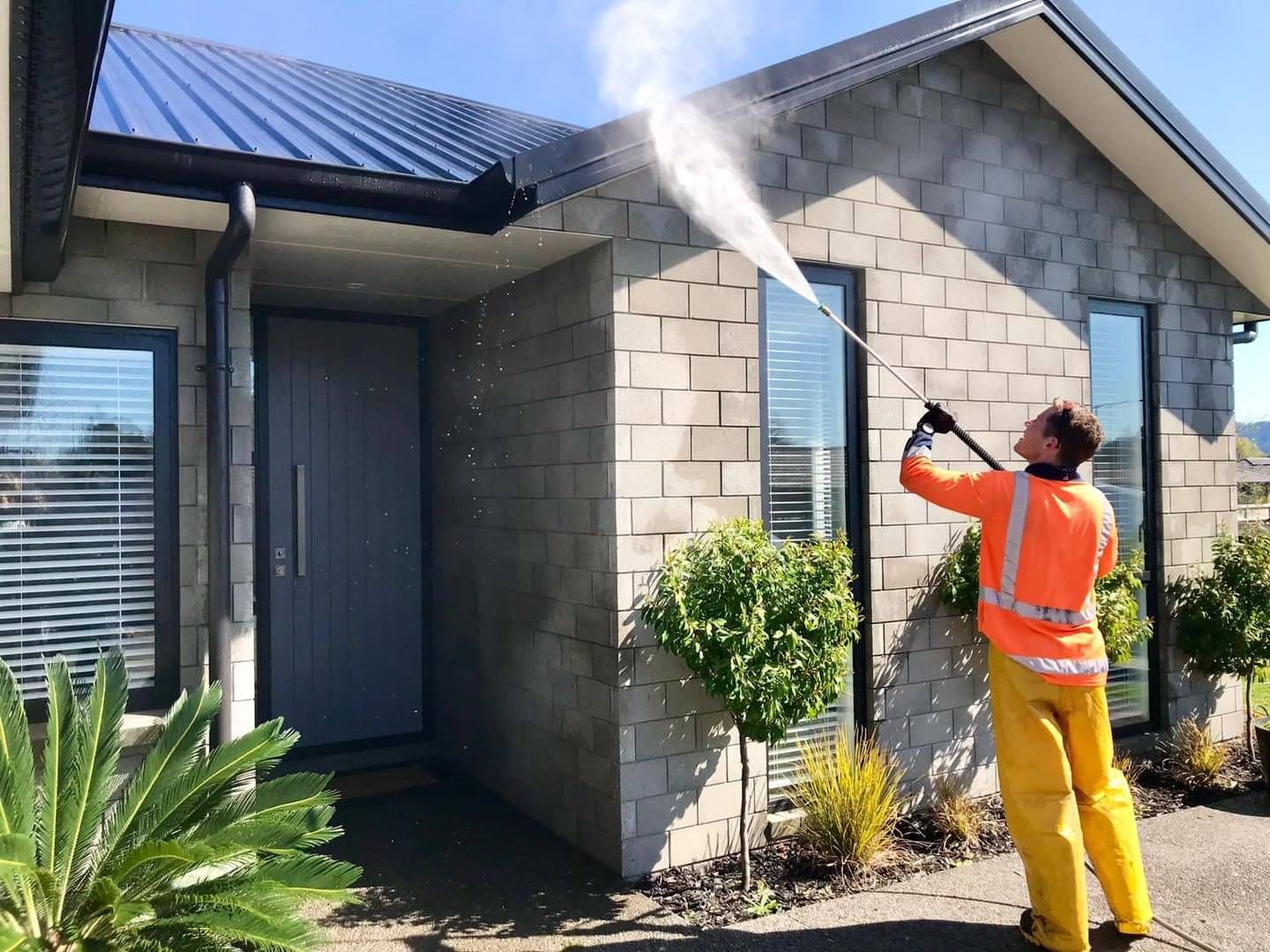 Worker on roof cleaning gutters