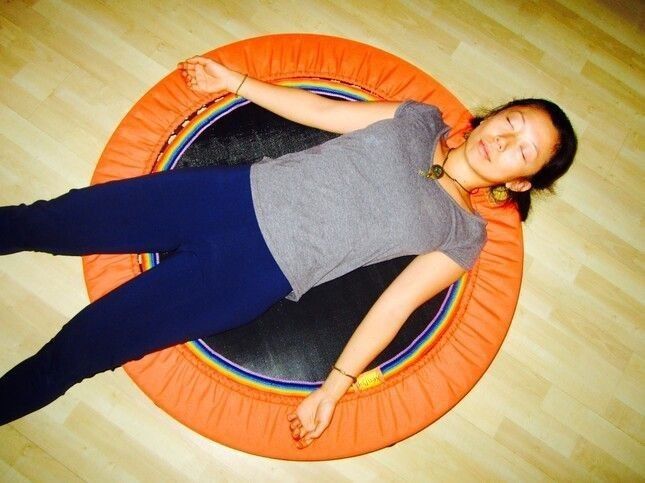 young woman relaxing on a XenPod Lymphaciser & Harmonic Energiser wellness mini-trampoline