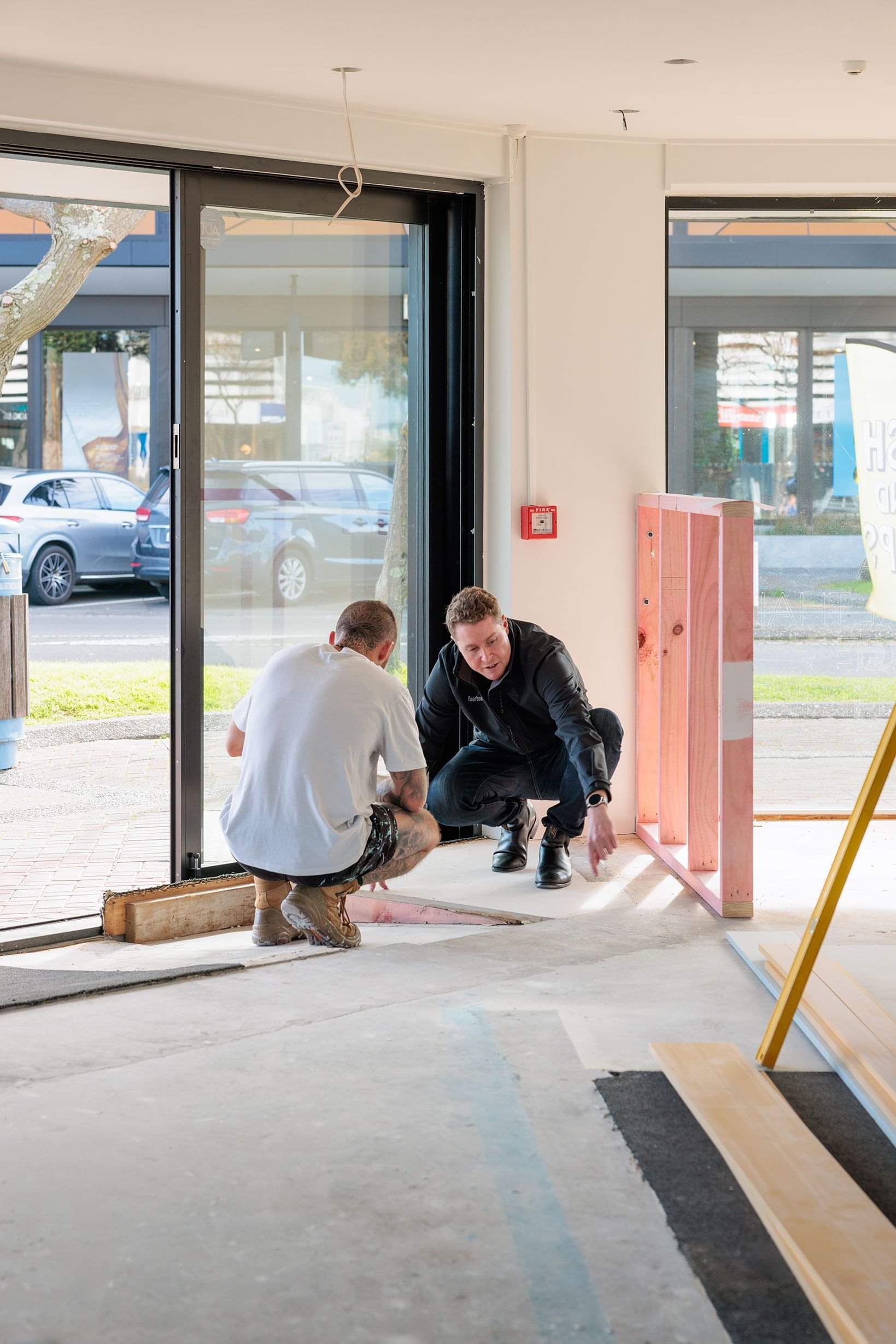 Mitch from Floorboards Tauranga advising builders on timber flooring installation in a room under construction with concrete floors.