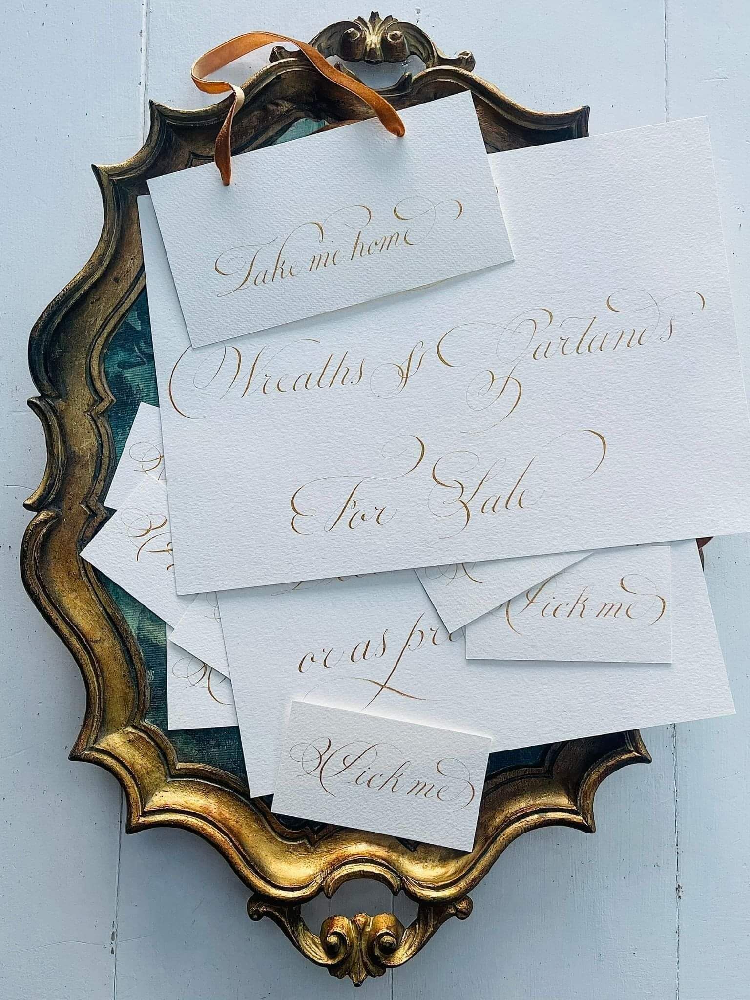 Pick Me’ sign hand-inked in copperplate calligraphy with elegant flourishes, displayed on an ornate tray.