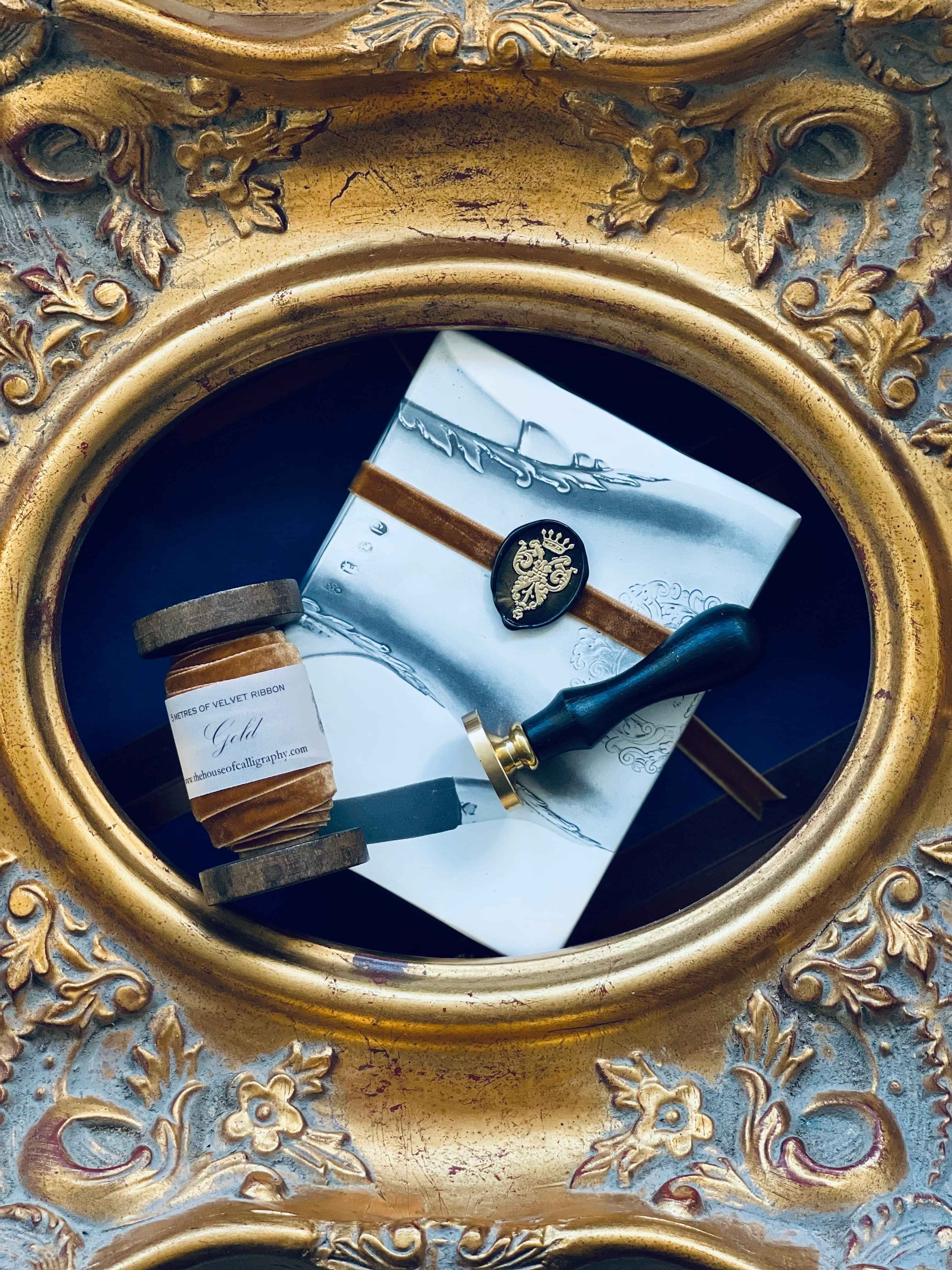 A gilded frame with a gold velvet ribbon, ornate wax seal and stamp inside