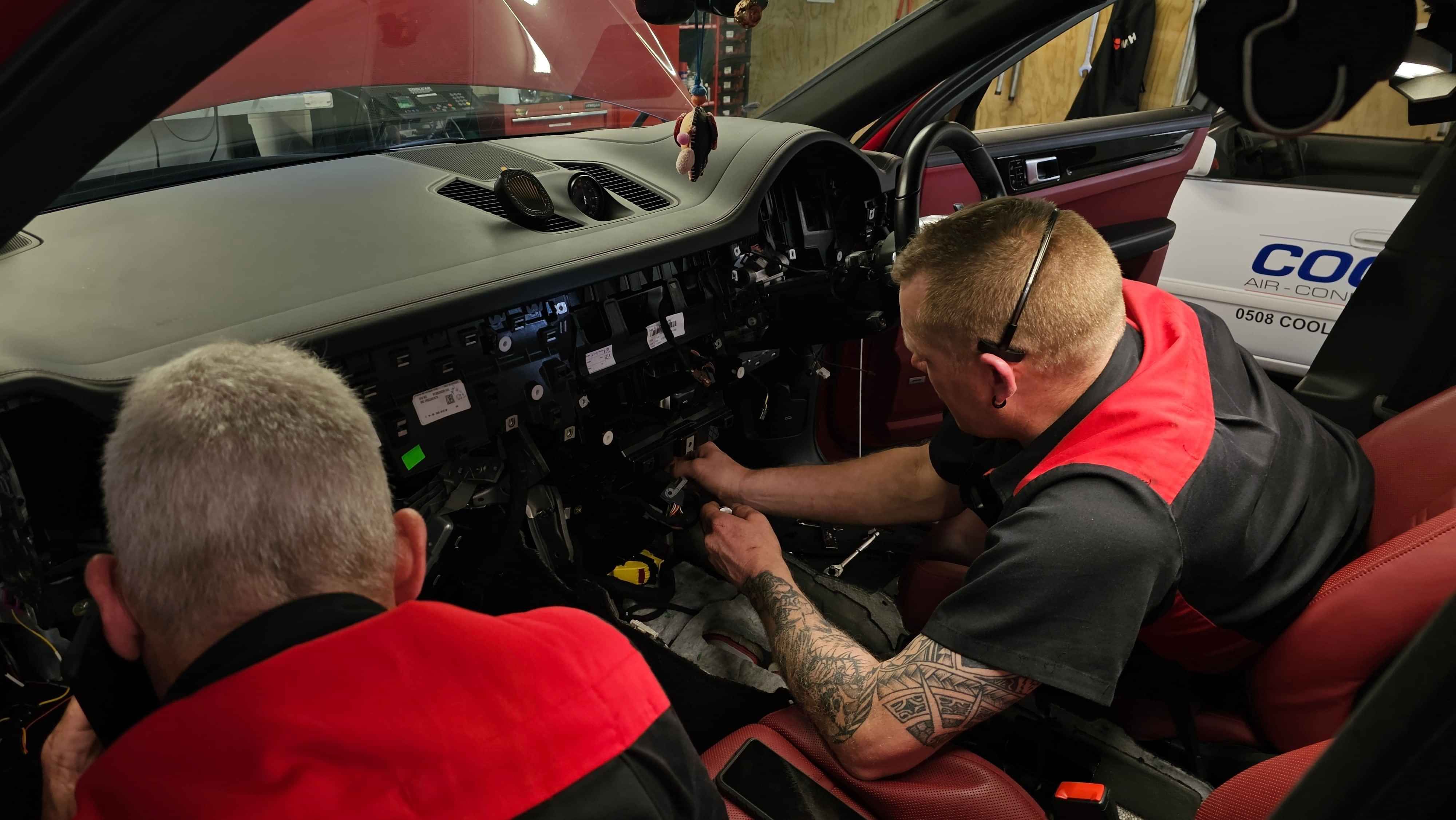 Two CoolCar technicians removing dashboard of Porsche Cayanne to remove and replace leaking evaporator