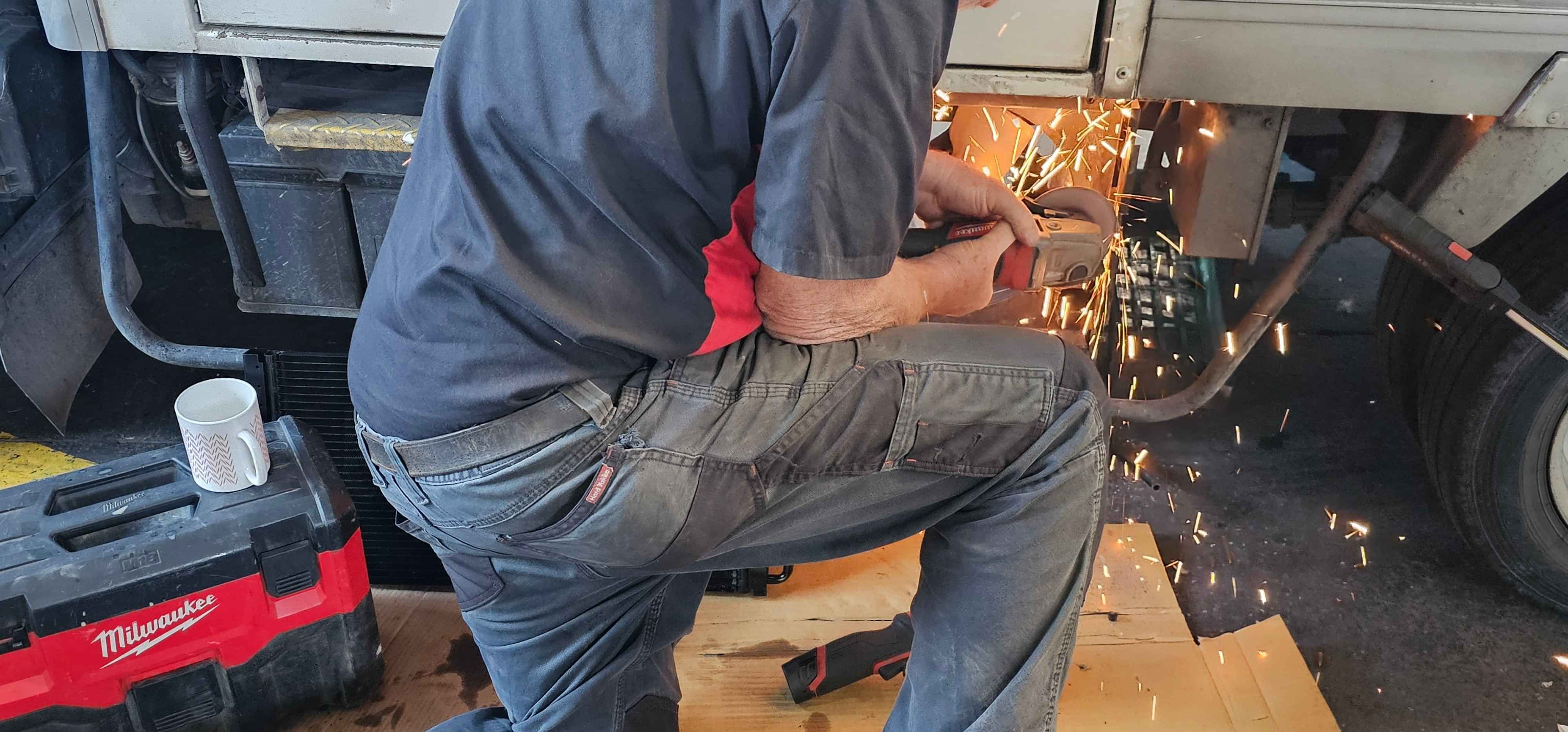 CoolCar Technician using grinder to modify mount to fit A/C part