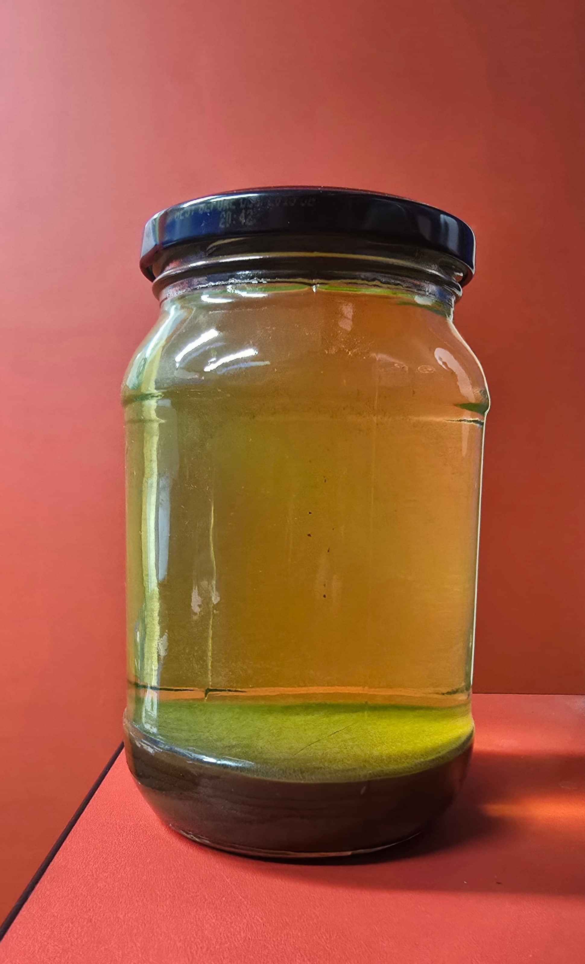 Mixture of red and green anti-freeze creating brown sediment in bottom of  jar of green antifreeze. 