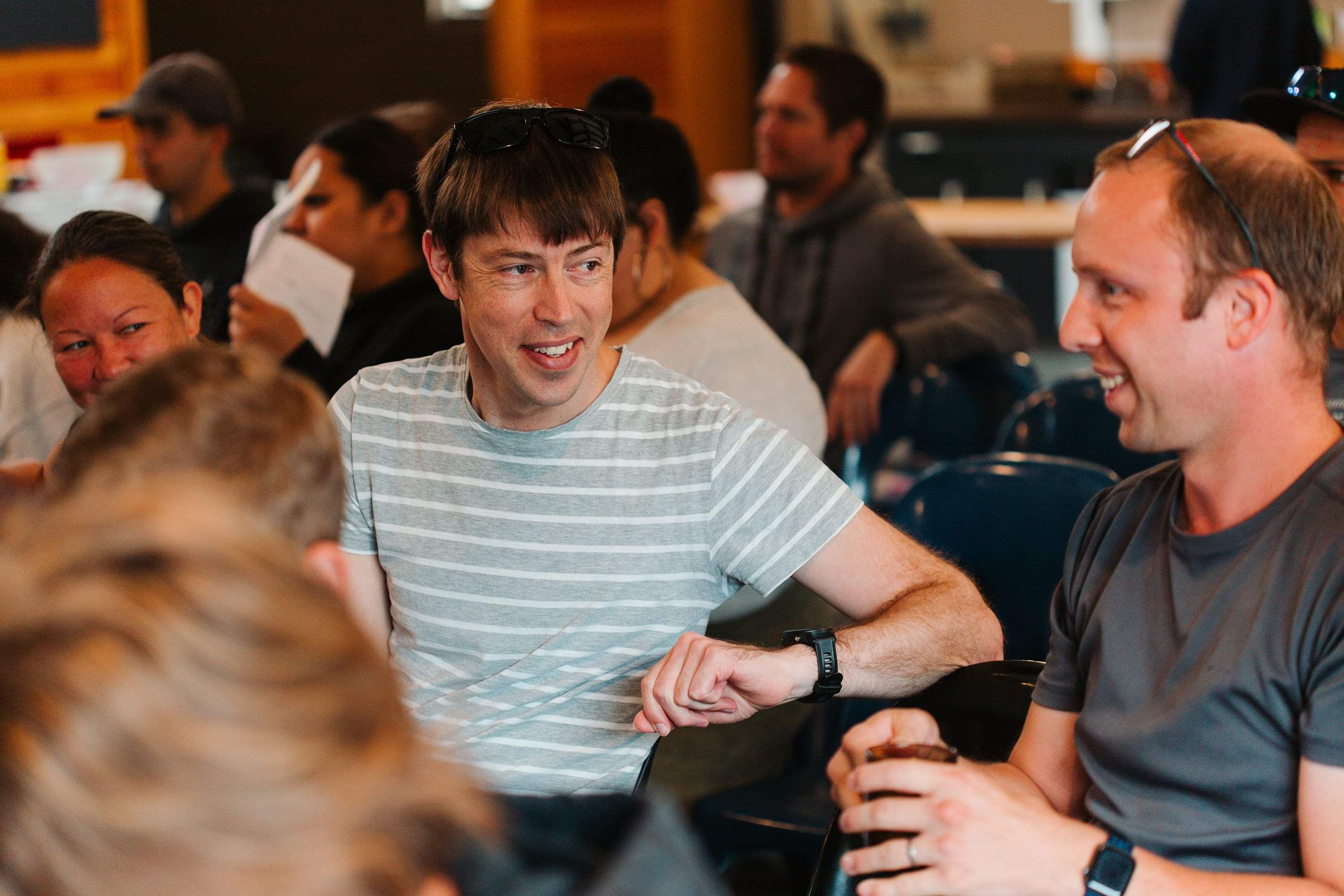 Smiling men in late 40s talk before service starts.