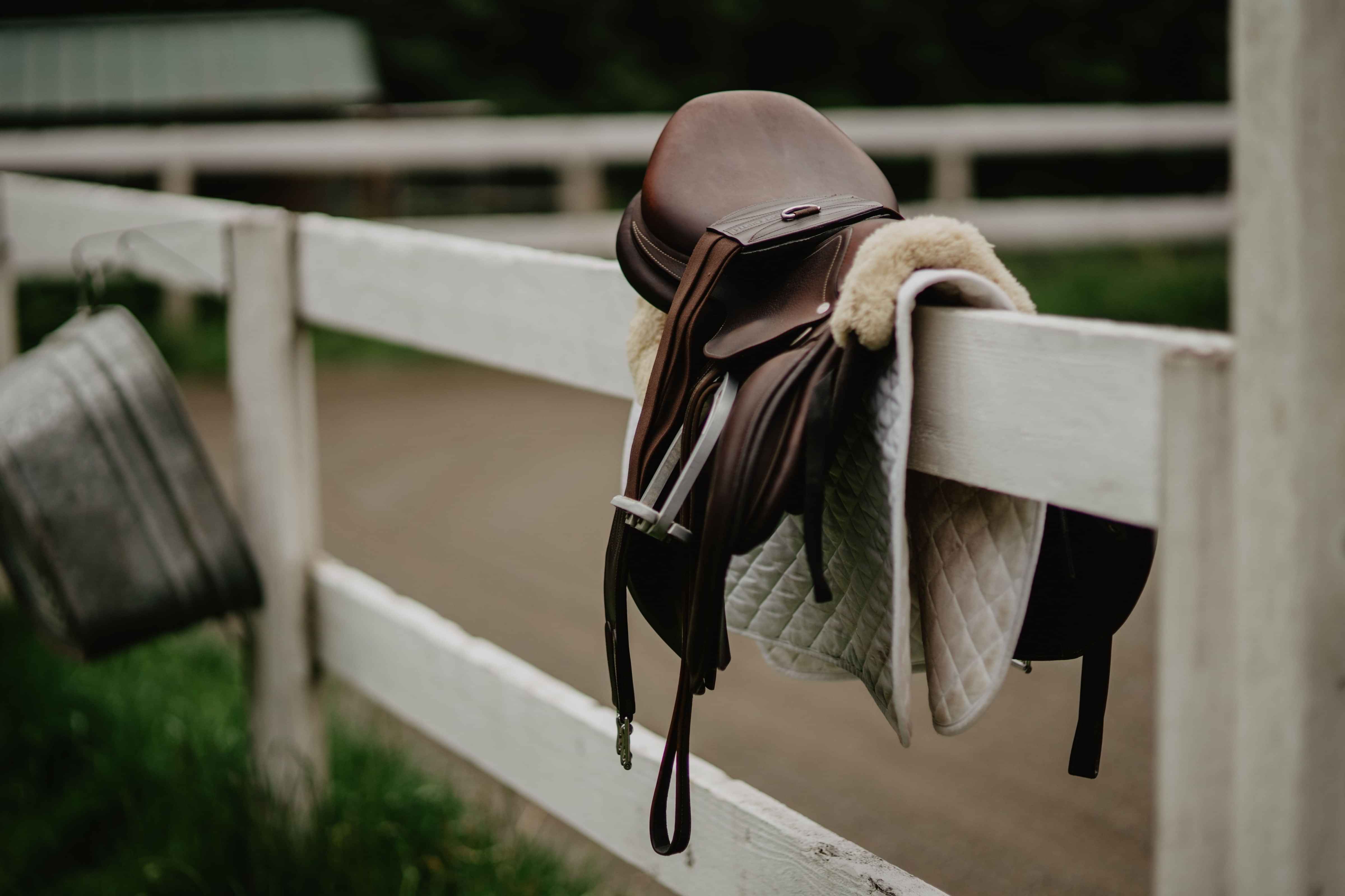 Brown Saddle and Tapestry Girth on a saddle blanket and white fence