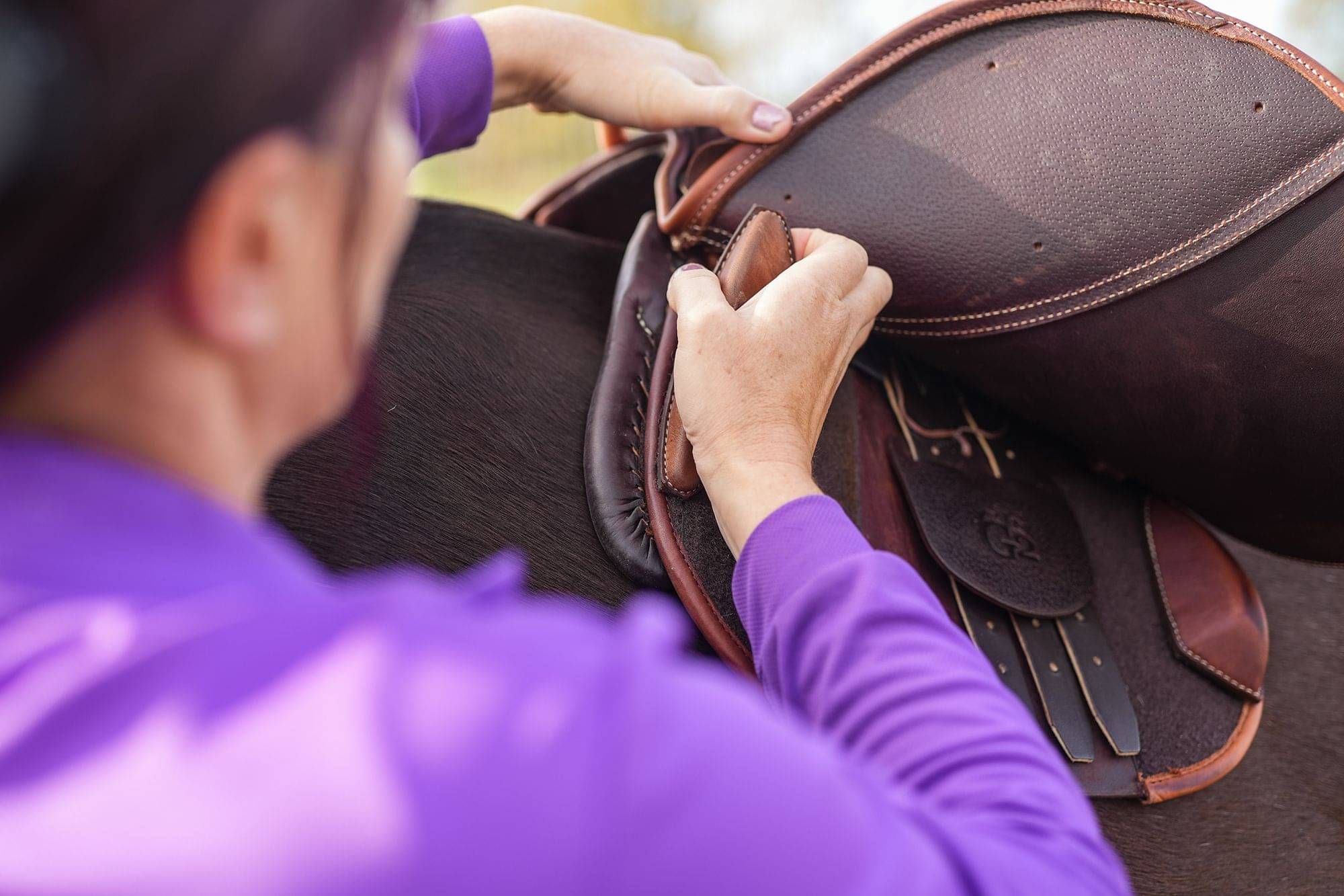 Christine, holistic saddle fitter fitting accessories to horse