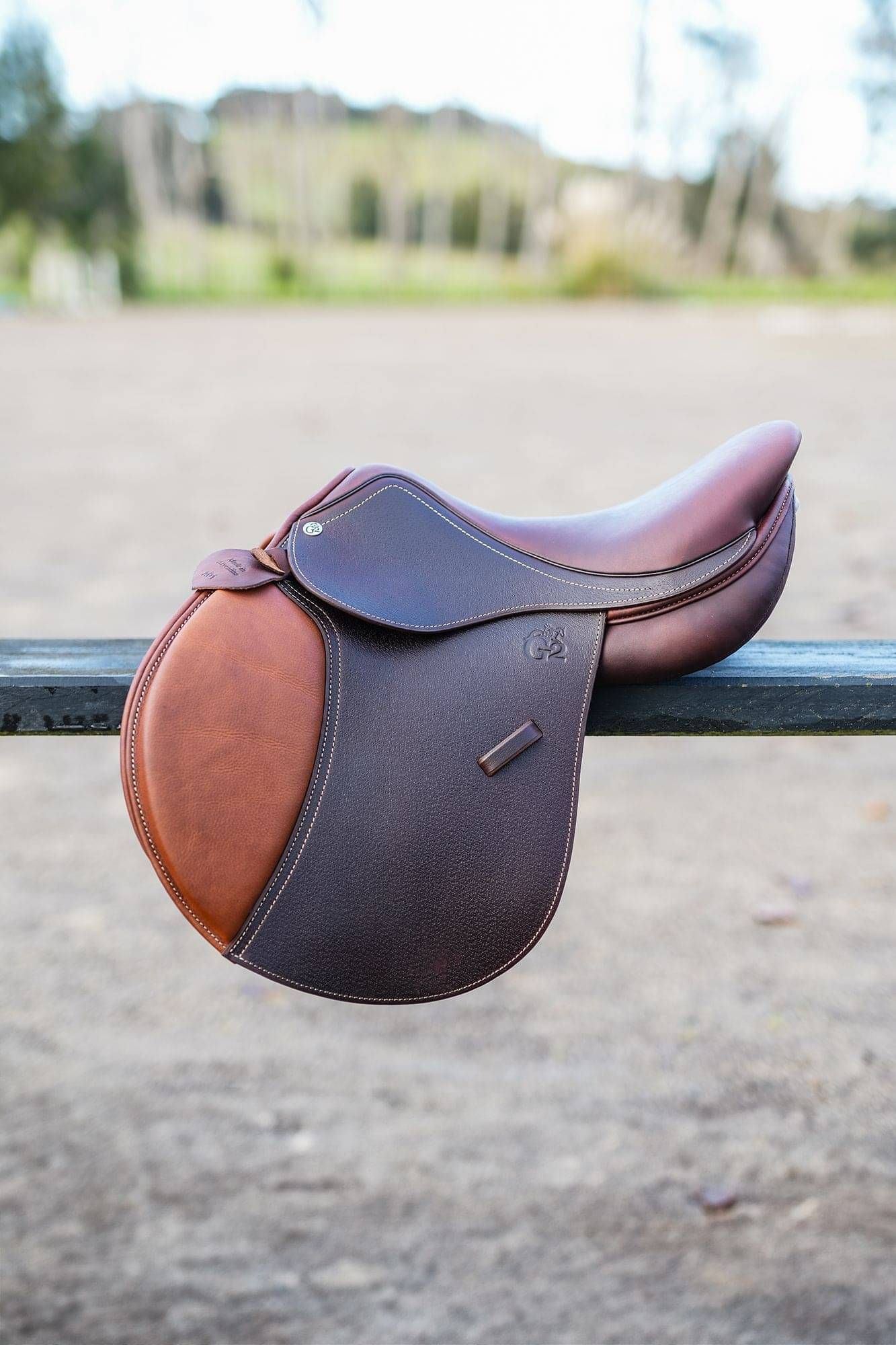 Brown Saddle and Tapestry Girth on a saddle blanket and white fence