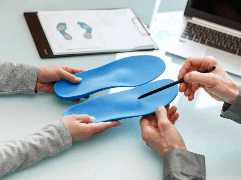 Clinician showing a patient custom blue orthotic insoles