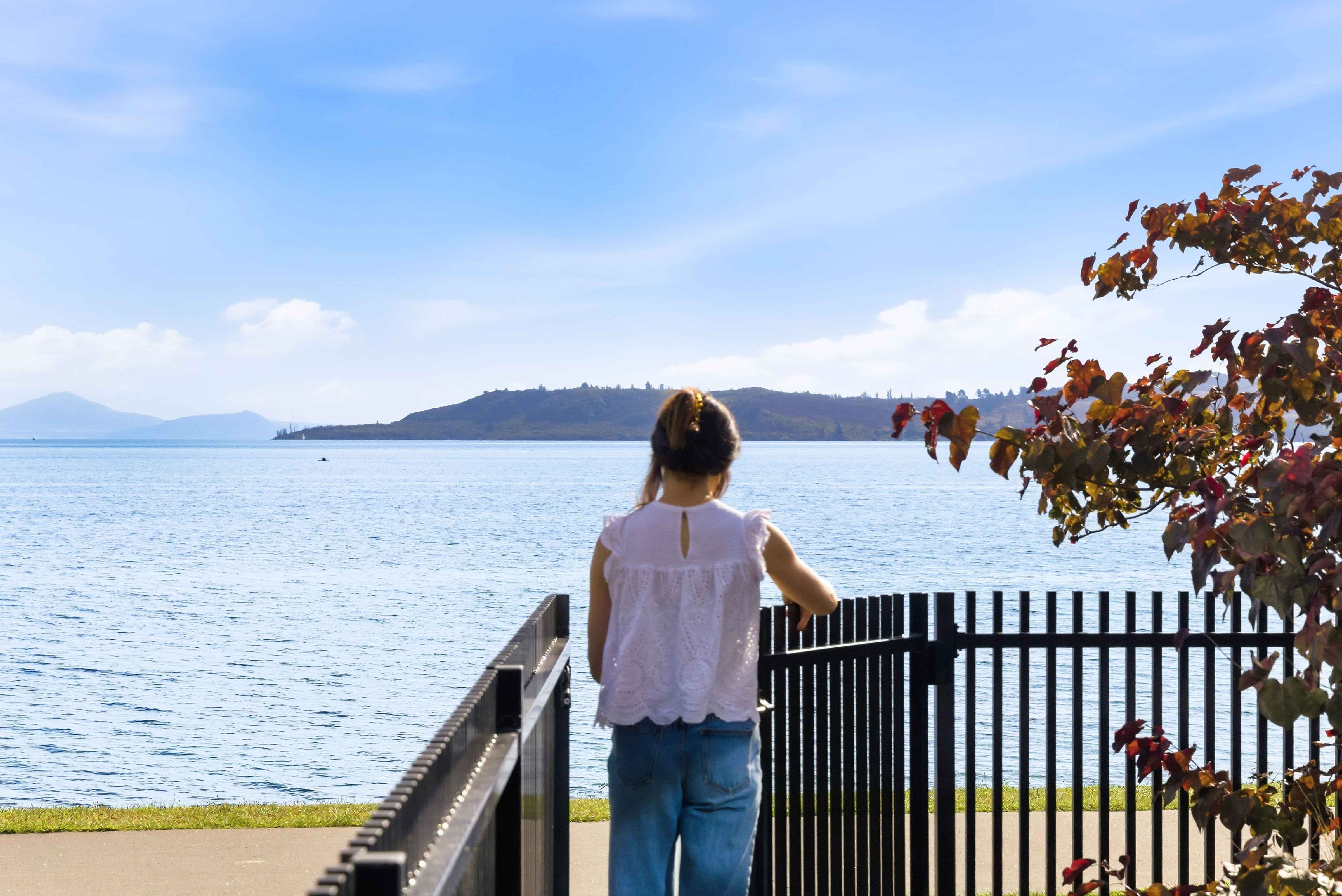 Guest looking out over Lake Taupo from the lakefront walkway at Roam Taupo
