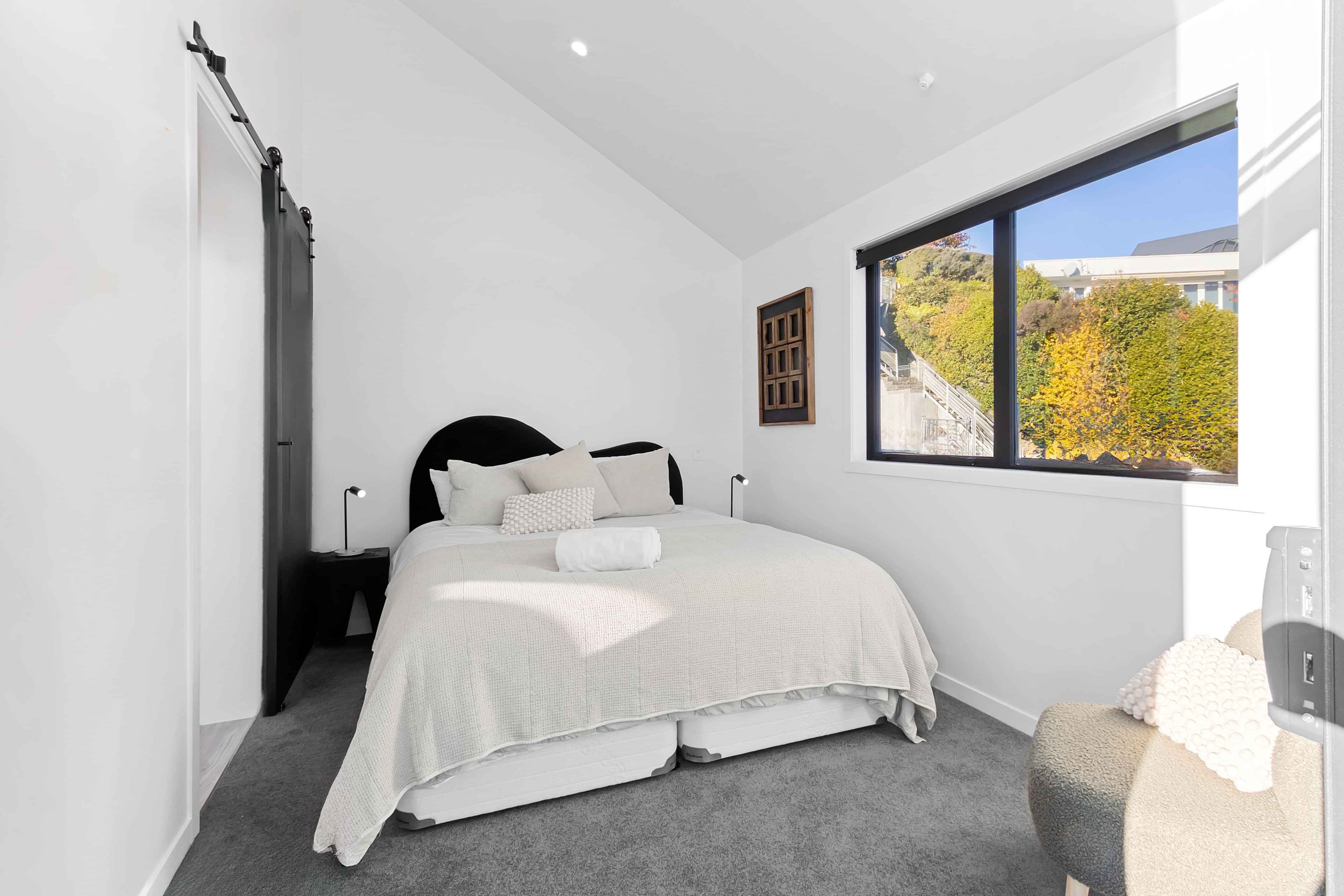 King bed with lake and mountain views in the master bedroom of a Roam Taupo lakefront unit