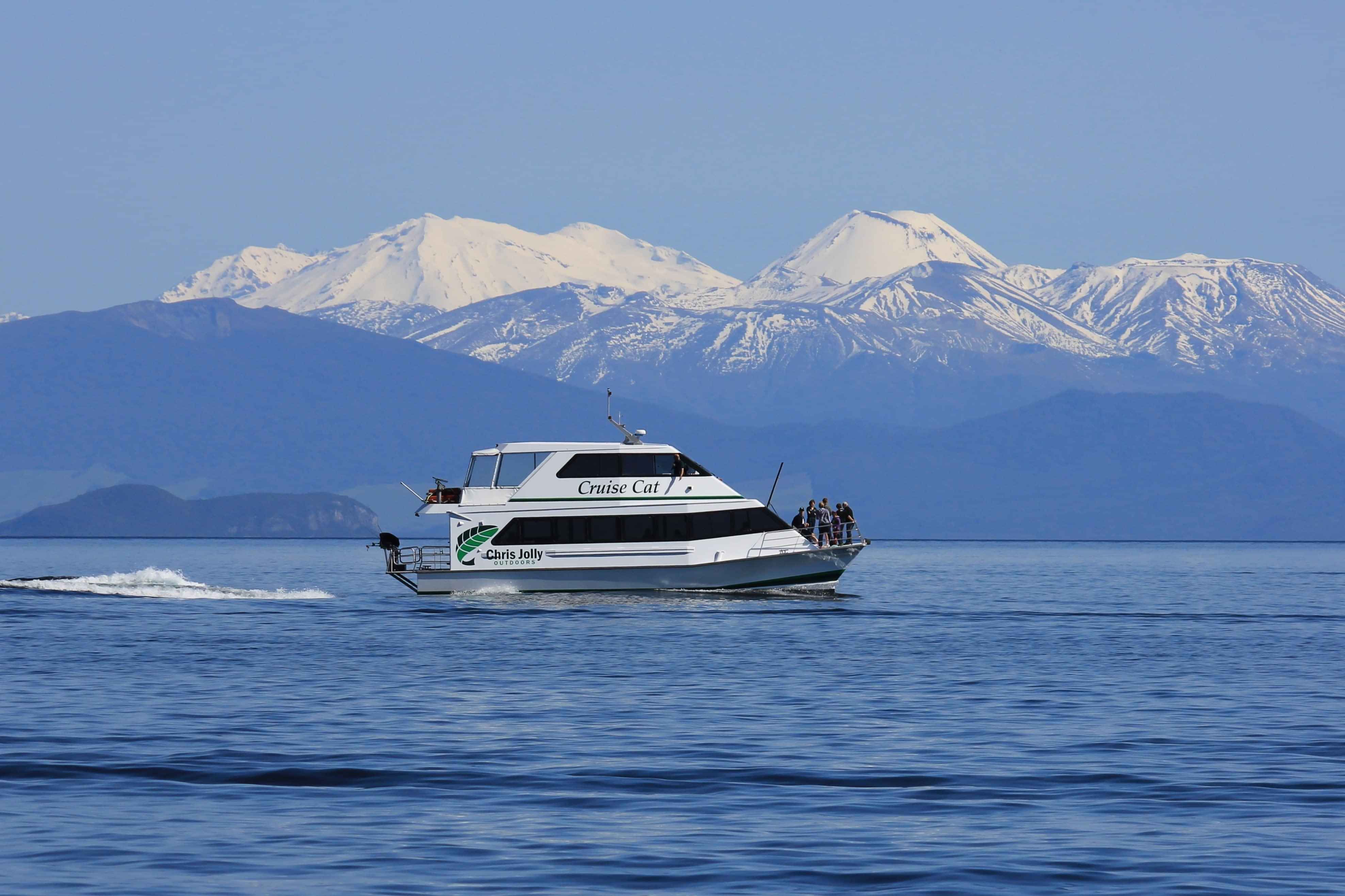 Chris Jolly Outdoors cruise boat on Lake Taupo with snow-capped volcanic peaks in the background