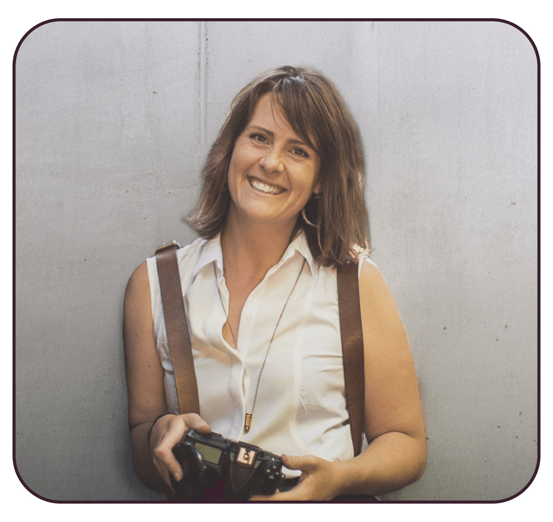 Brenna, our Graphic designer & photographer smiling while holding a camera