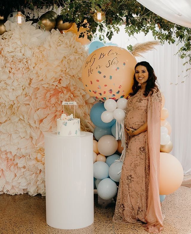 pregnant woman posing in front of the baby shower backdrop