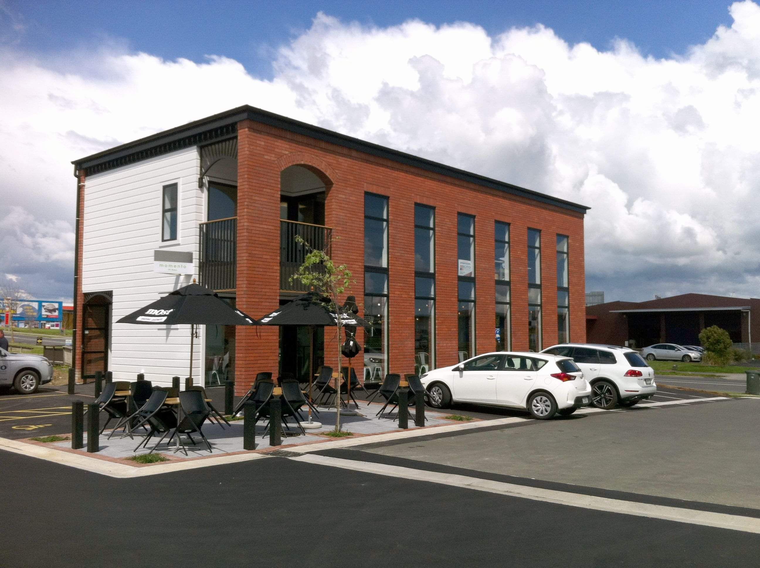 Modern office space with wooden table, chairs, leather couch, white rug, painting, and plant