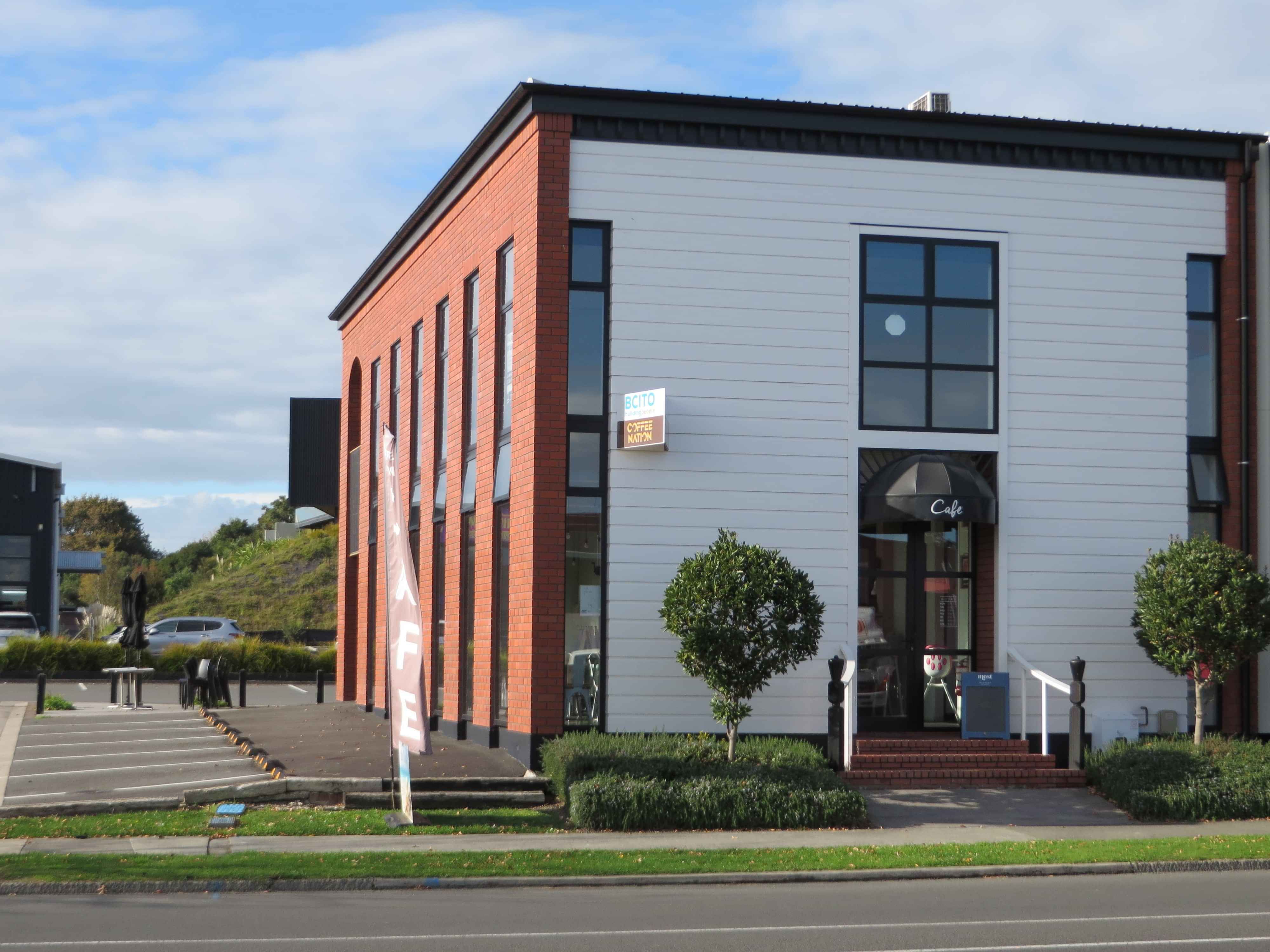 Modern waiting room with blue couch, round coffee table with plant, white vase, and painting on the wall.