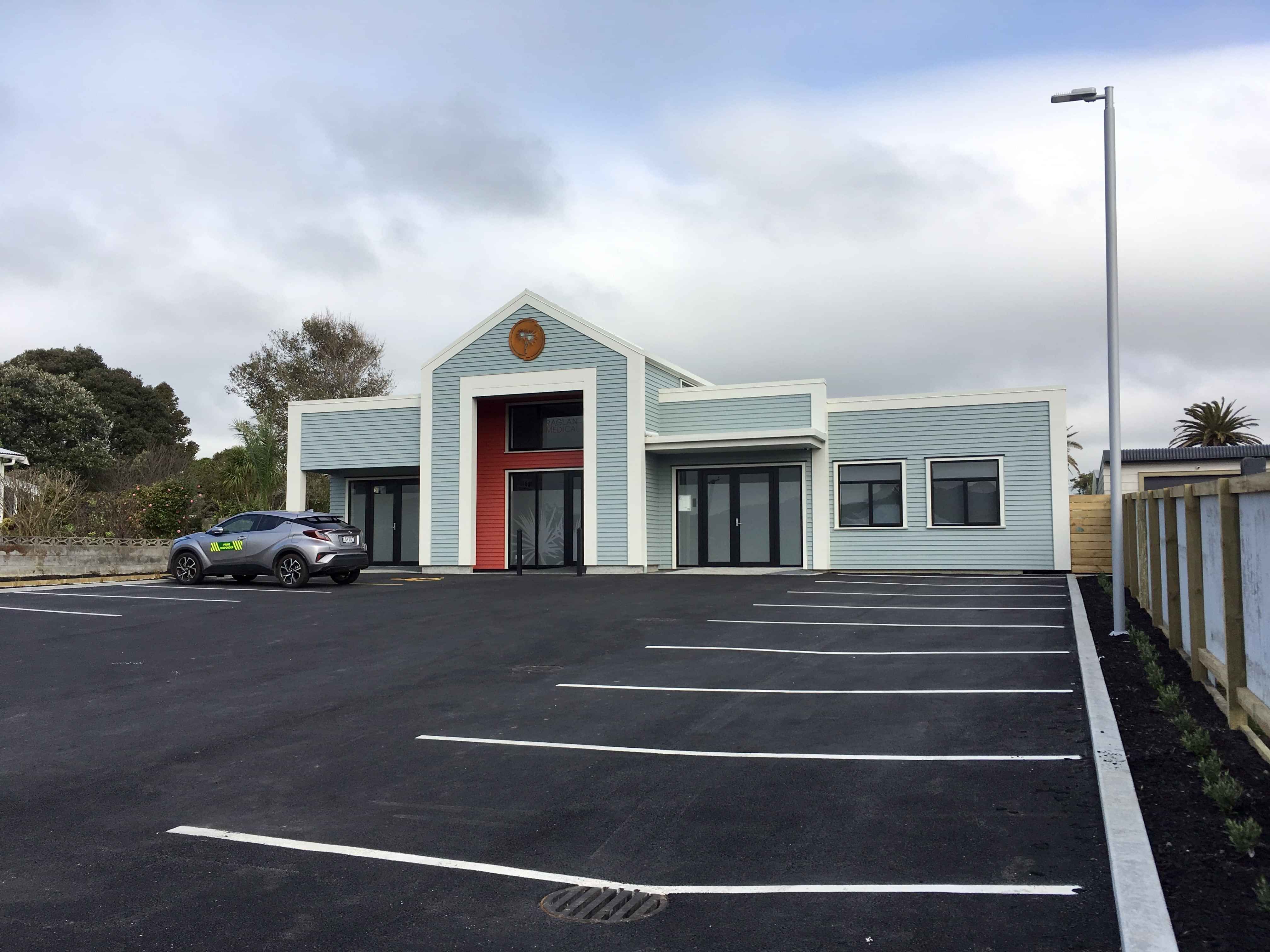 Modern office space with wooden table, chairs, leather couch, white rug, painting, and plant
