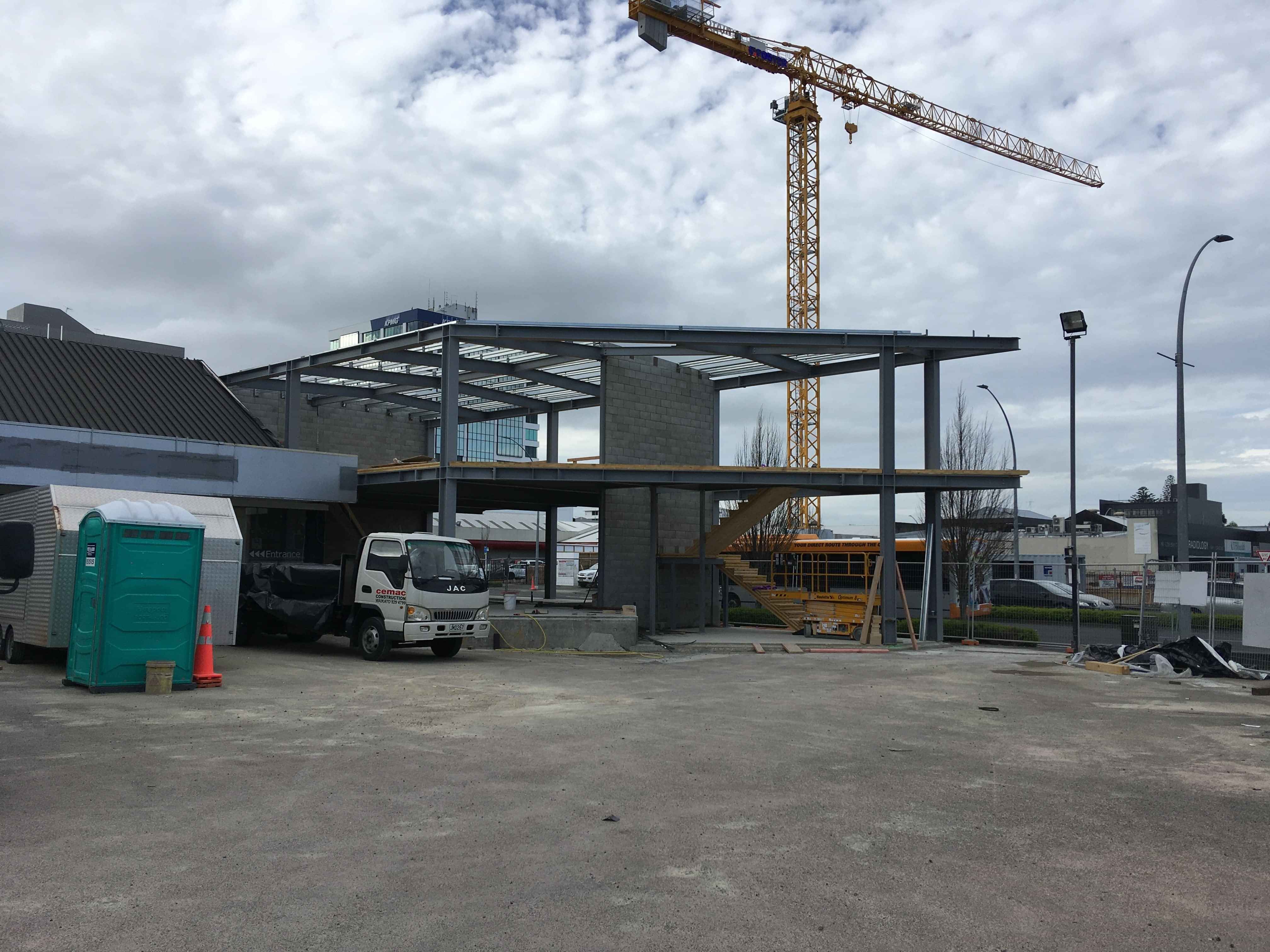 Modern waiting room with blue couch, round coffee table with plant, white vase, and painting on the wall.