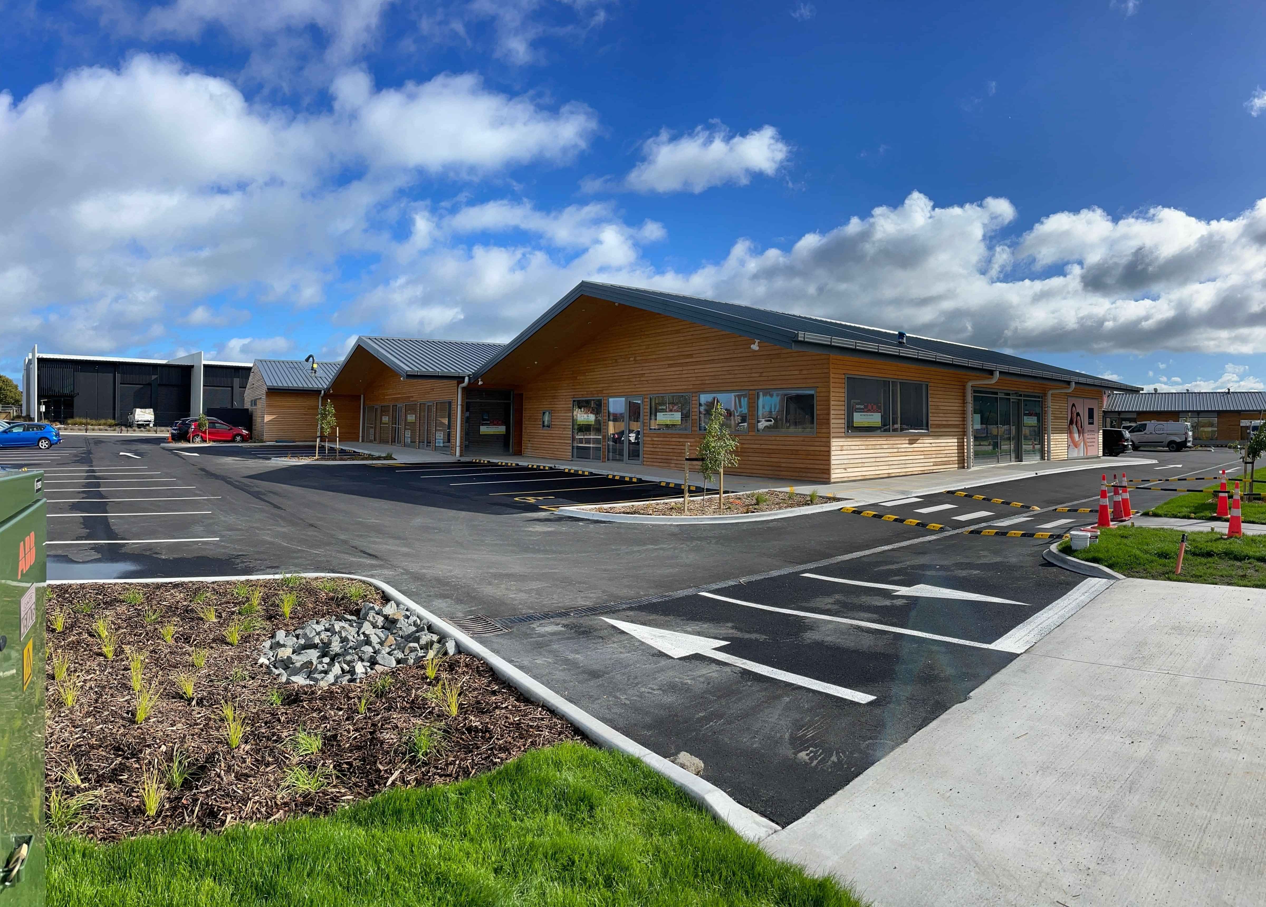 Modern office space with wooden table, chairs, leather couch, white rug, painting, and plant