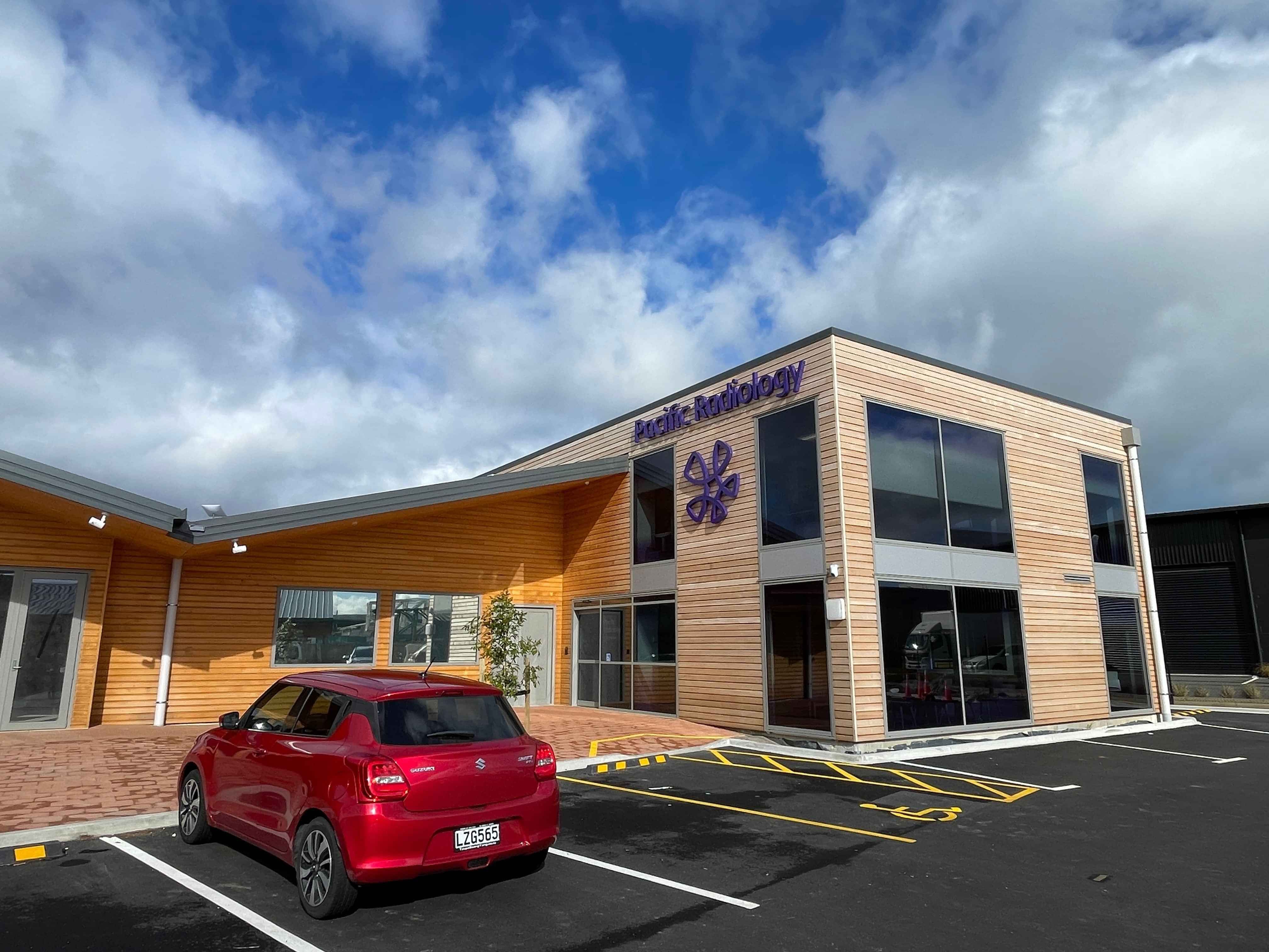 Modern waiting room with blue couch, round coffee table with plant, white vase, and painting on the wall.