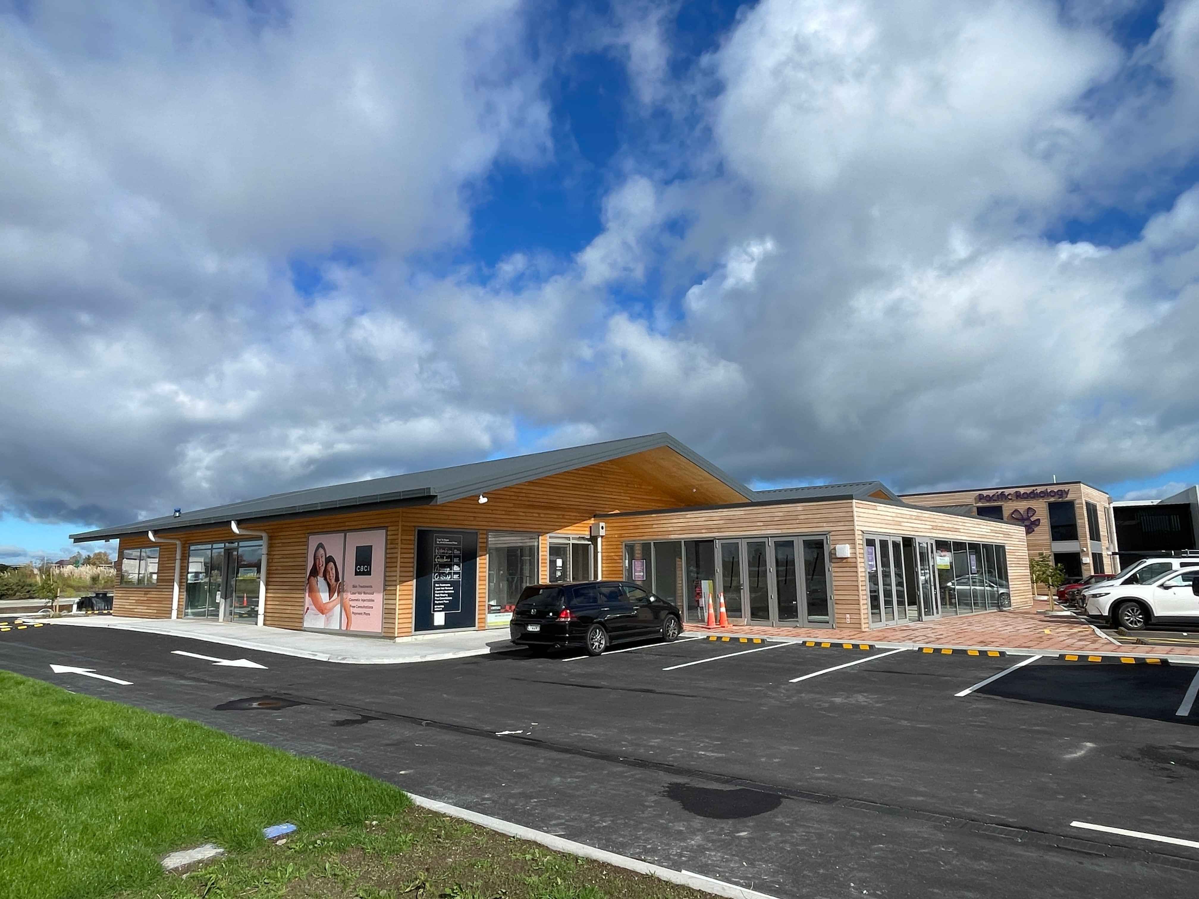 Modern waiting room with blue couch, round coffee table with plant, white vase, and painting on the wall.