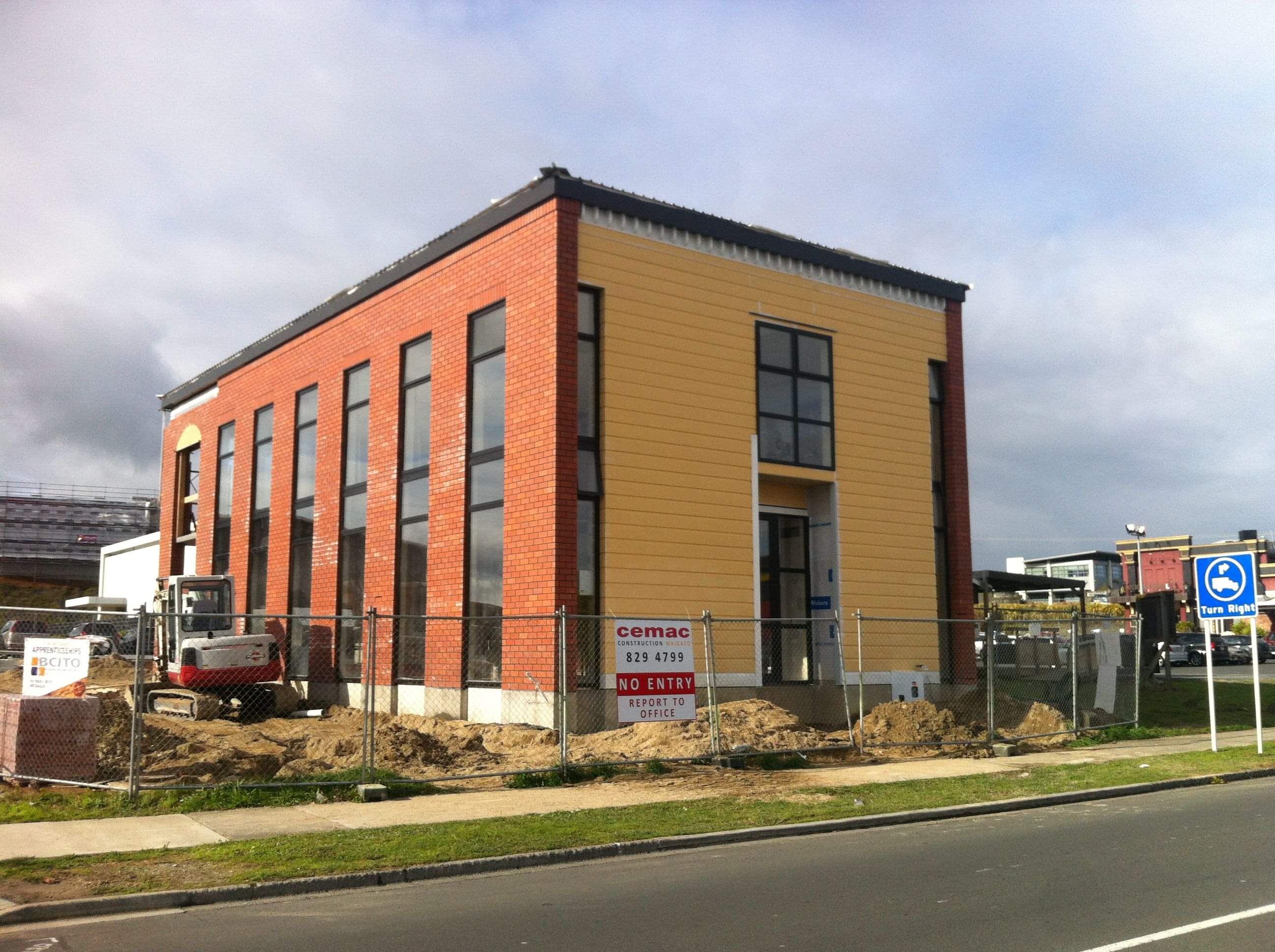 Modern waiting room with blue couch, round coffee table with plant, white vase, and painting on the wall.