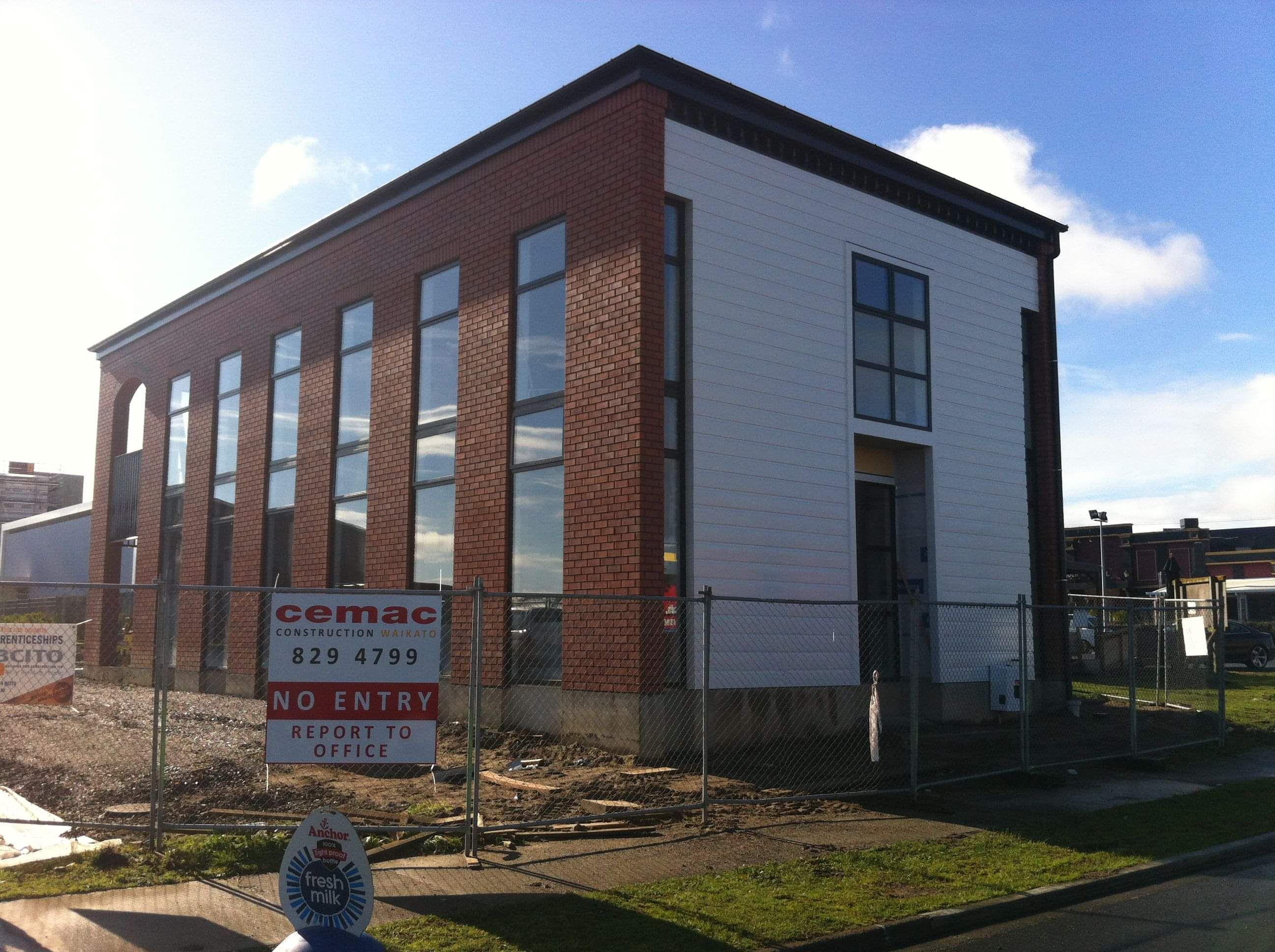 Modern waiting room with blue couch, round coffee table with plant, white vase, and painting on the wall.
