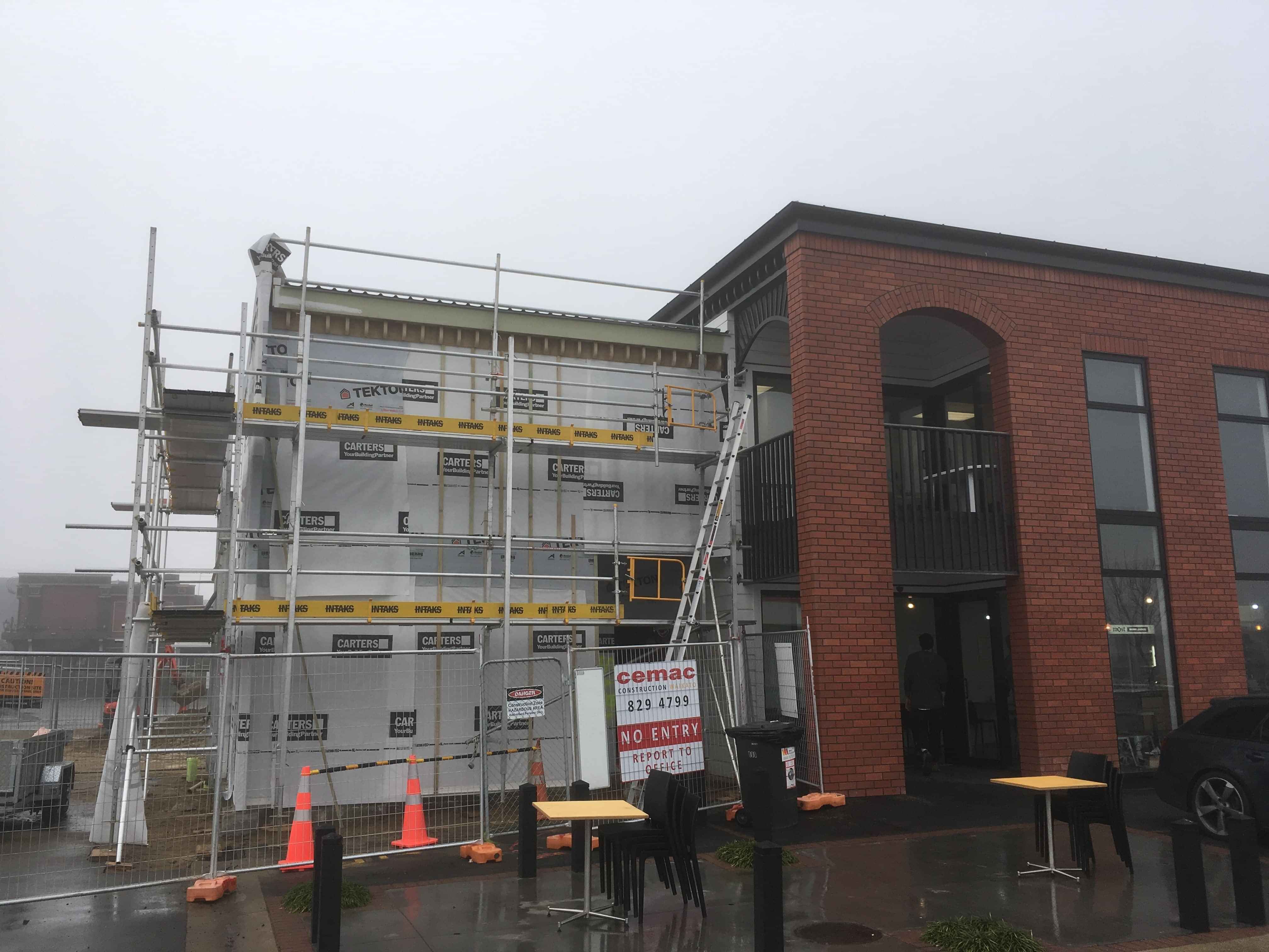 Modern waiting room with blue couch, round coffee table with plant, white vase, and painting on the wall.