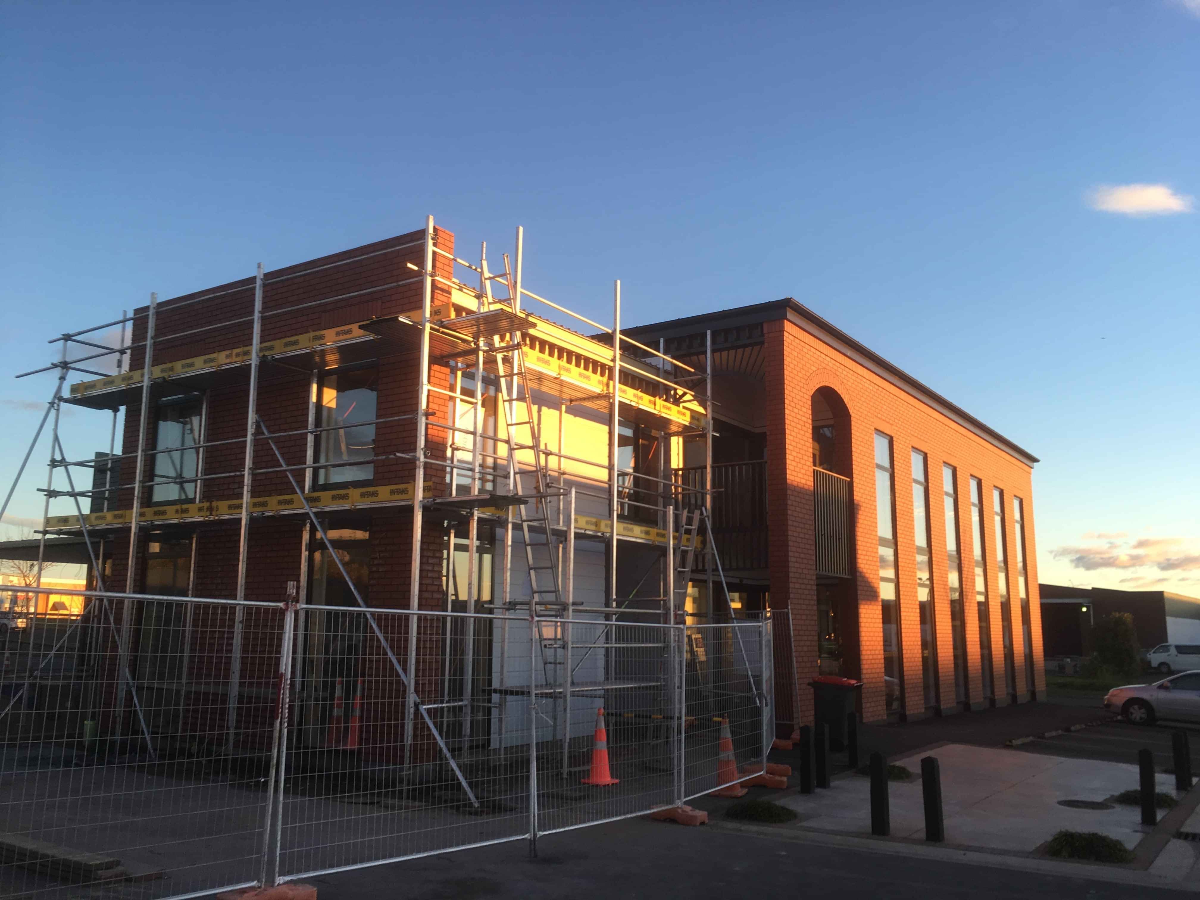 Modern waiting room with blue couch, round coffee table with plant, white vase, and painting on the wall.