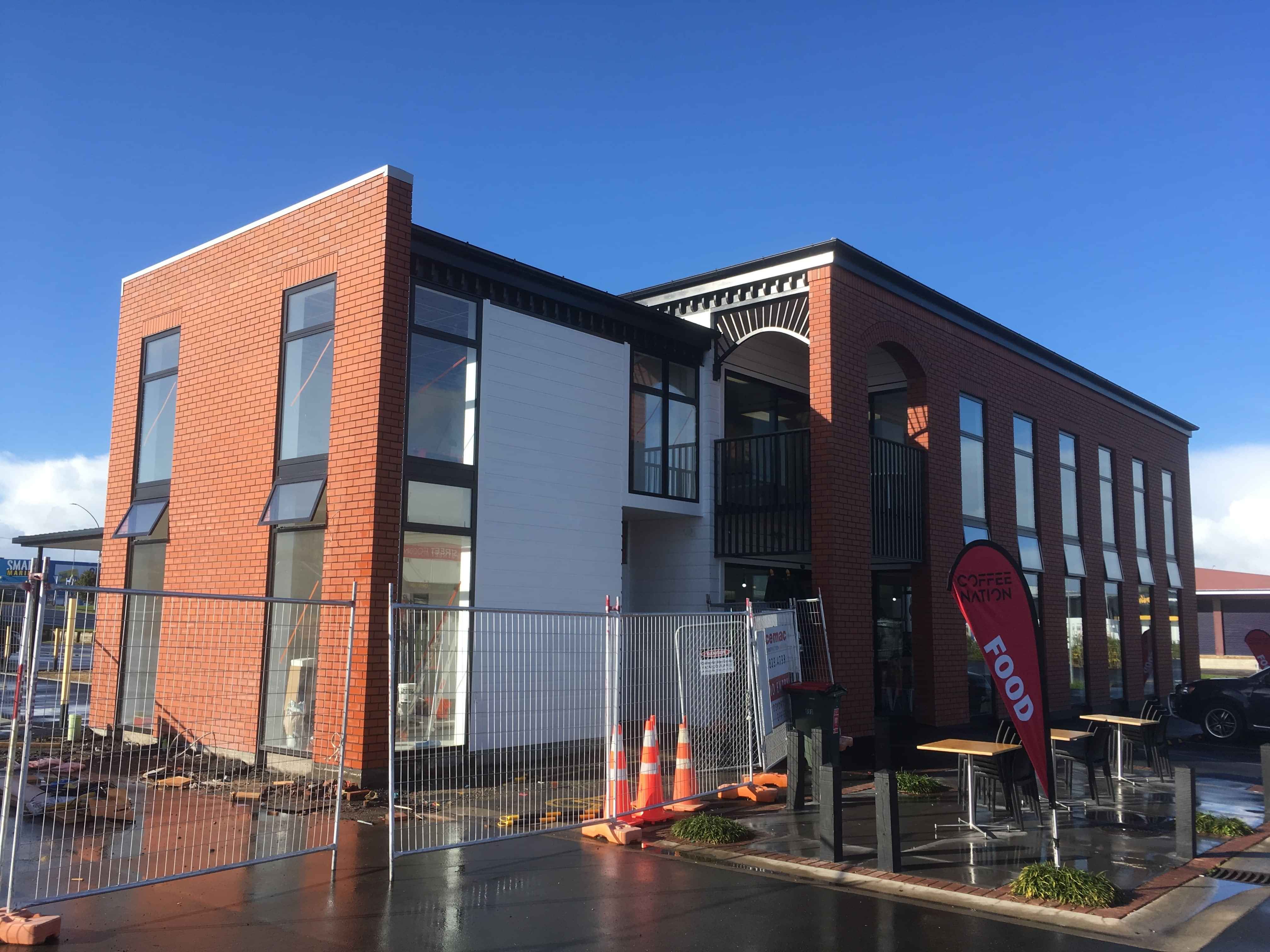 Modern waiting room with blue couch, round coffee table with plant, white vase, and painting on the wall.