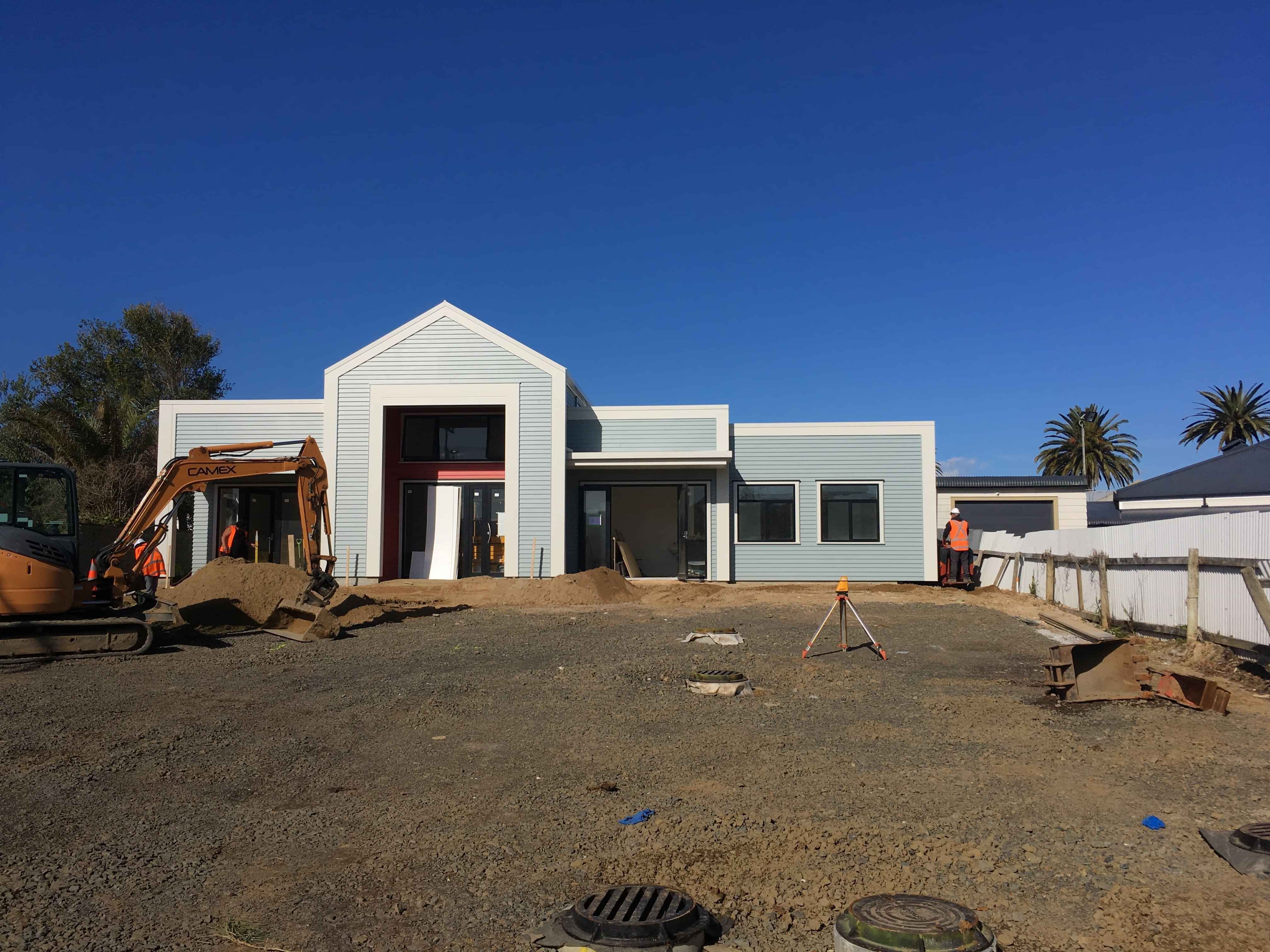 Modern waiting room with blue couch, round coffee table with plant, white vase, and painting on the wall.