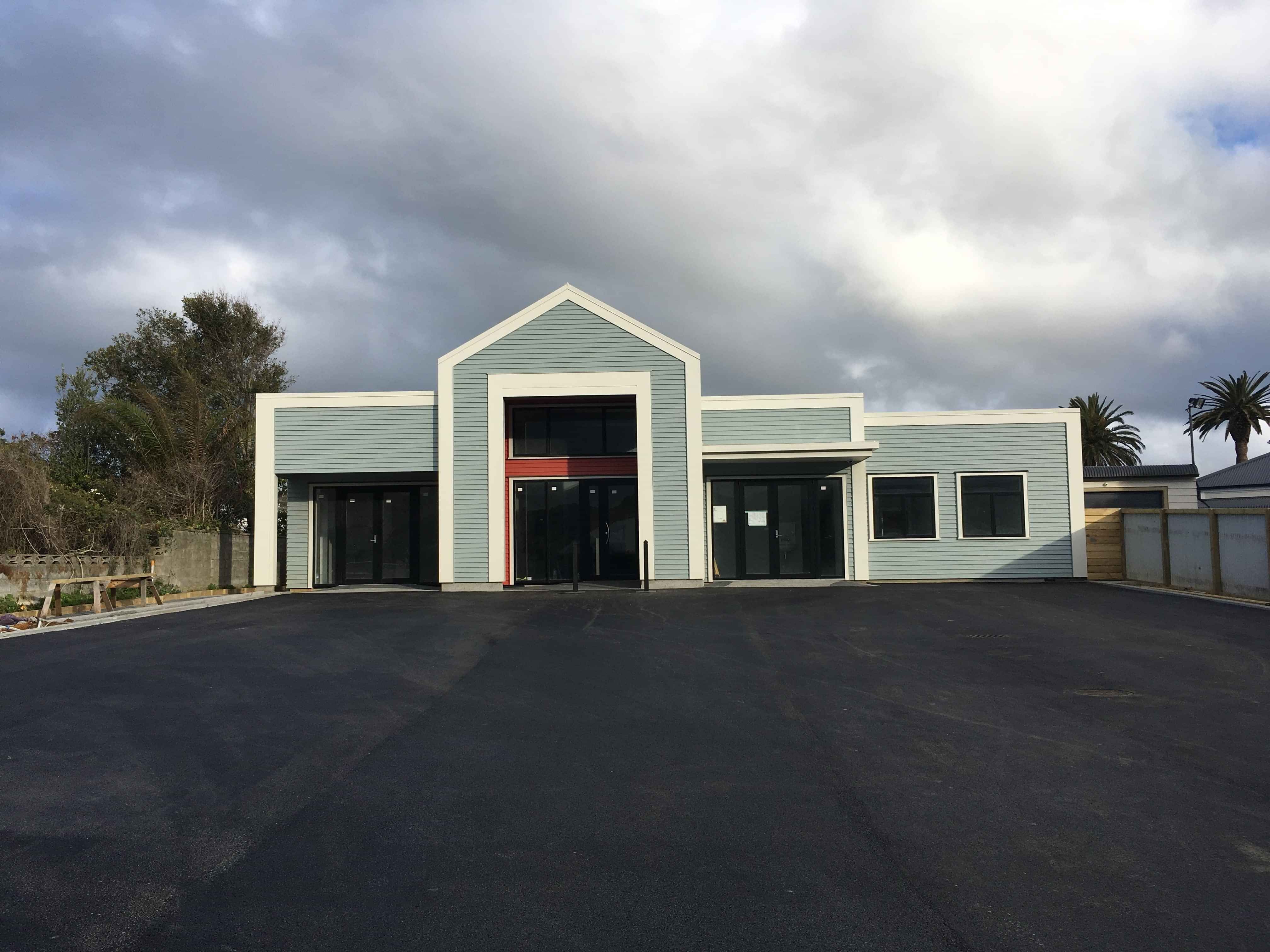 Modern waiting room with blue couch, round coffee table with plant, white vase, and painting on the wall.