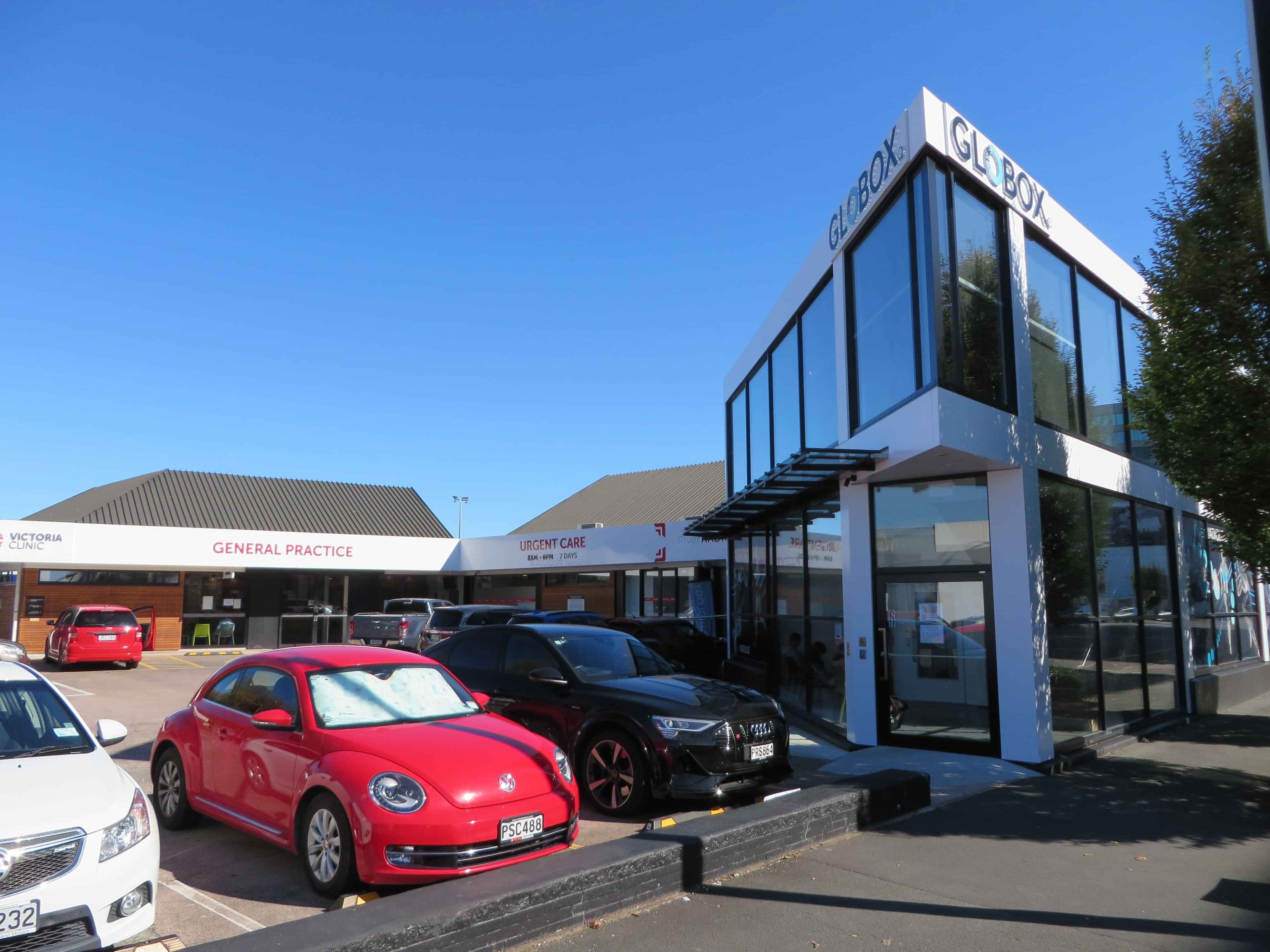 Modern waiting room with blue couch, round coffee table with plant, white vase, and painting on the wall.