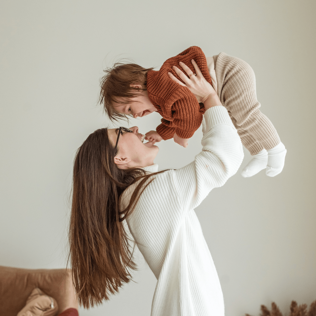 A Mum holding her child in the air - Māmā & Me Circle