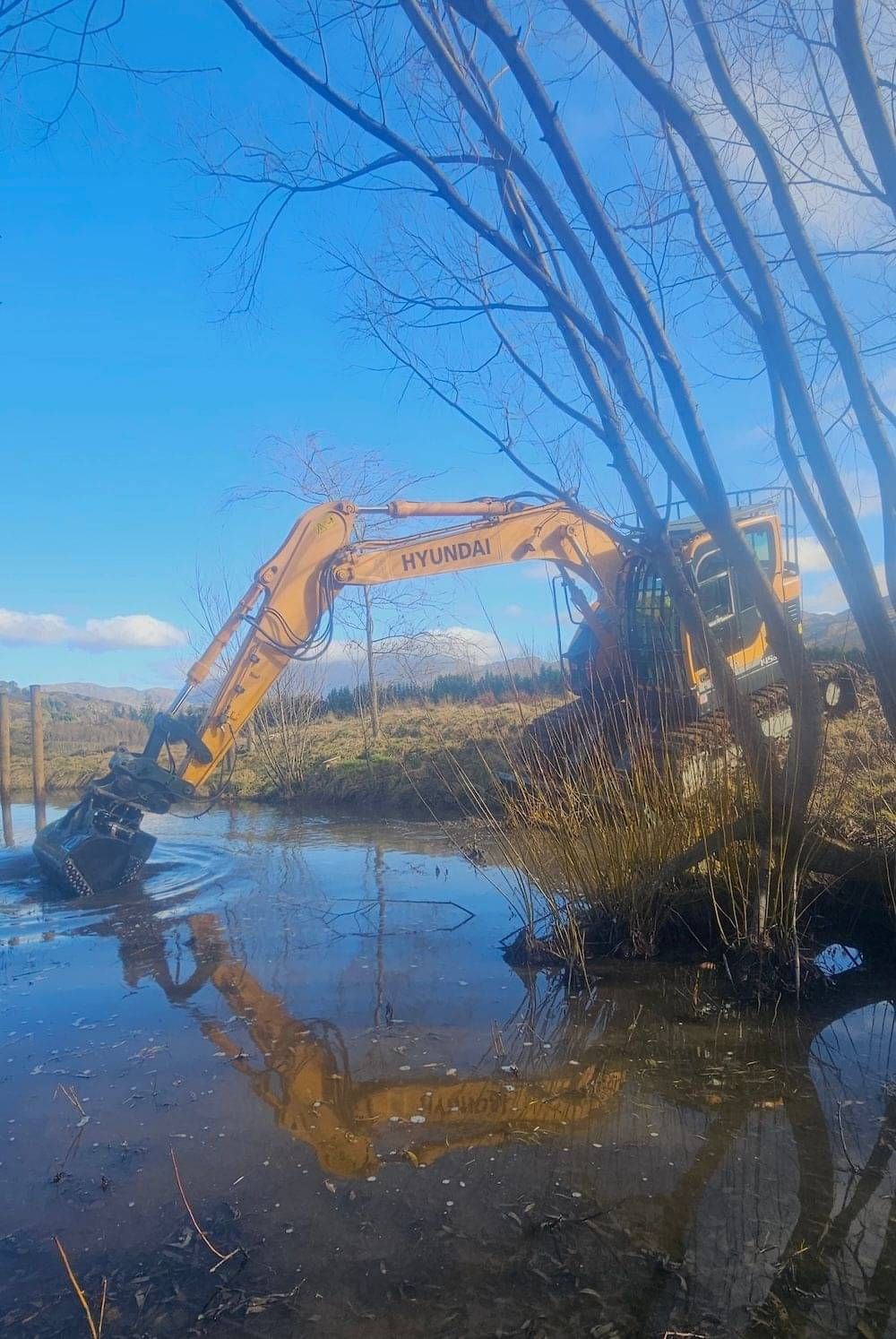 A digger mucking out and clearing out a pond on a property in Queenstown.