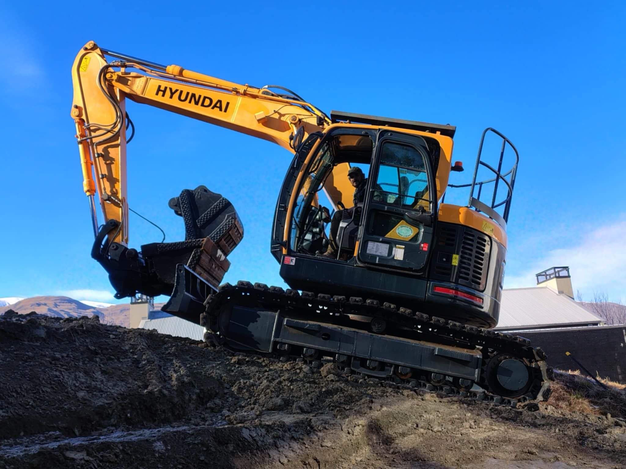 A Concrete & Earth Excavator making its way across dirt as it clears a section ready for building.