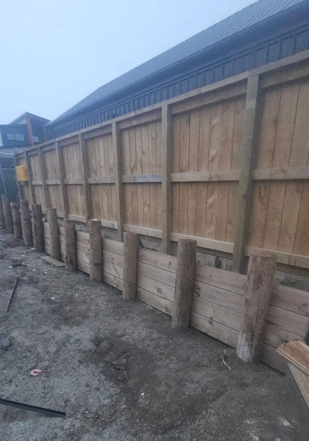 A timber retaining wall with wooden piles at a building site in Queenstown.