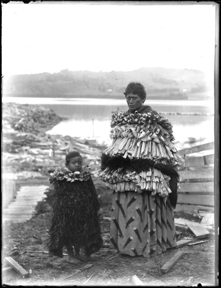 Photograph from the early 20th century of a Māori woman and child in rain cloaks.