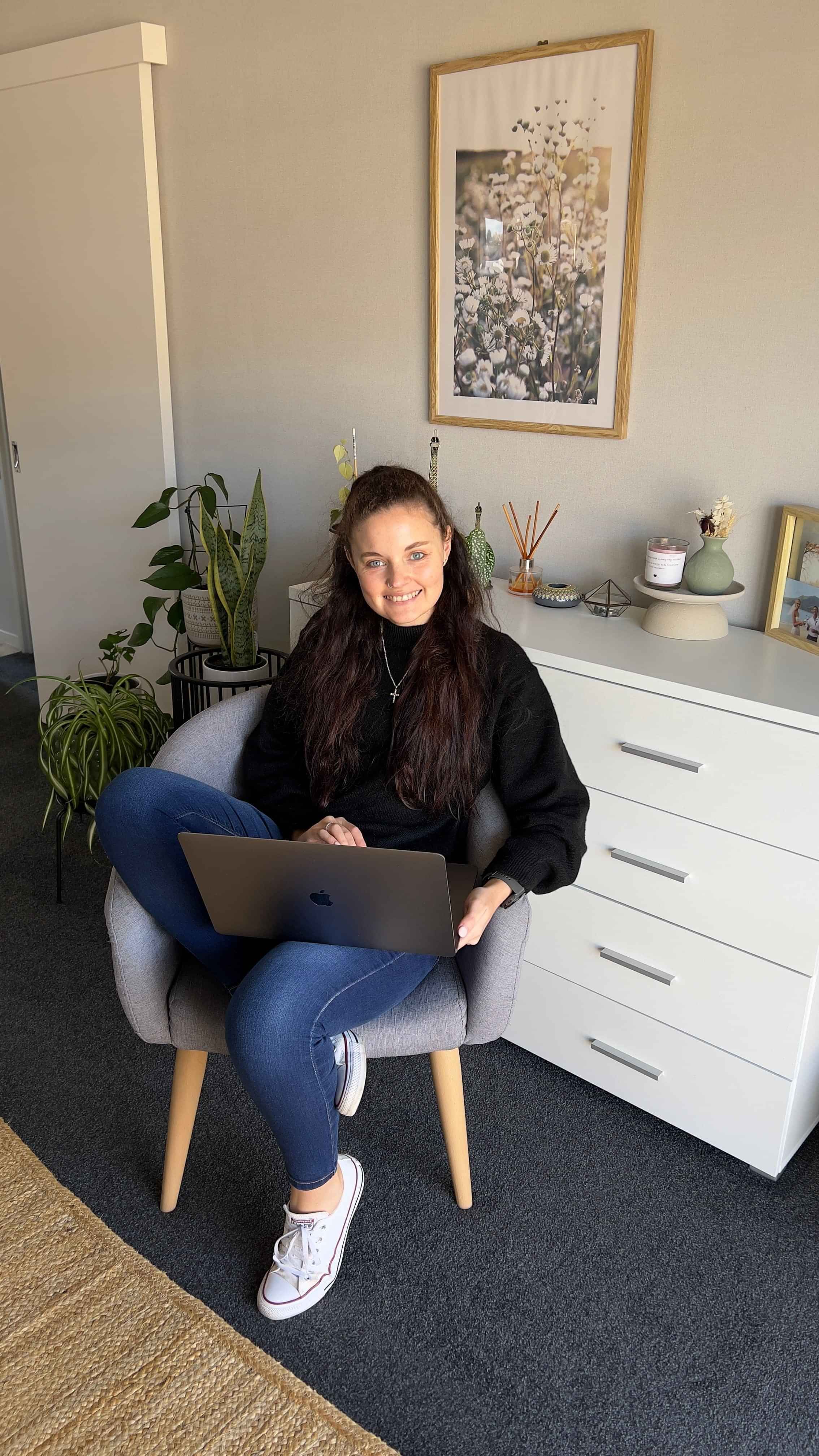 Laykanne Coetzee, freelance graphic designer based in New Zealand, sitting with laptop.