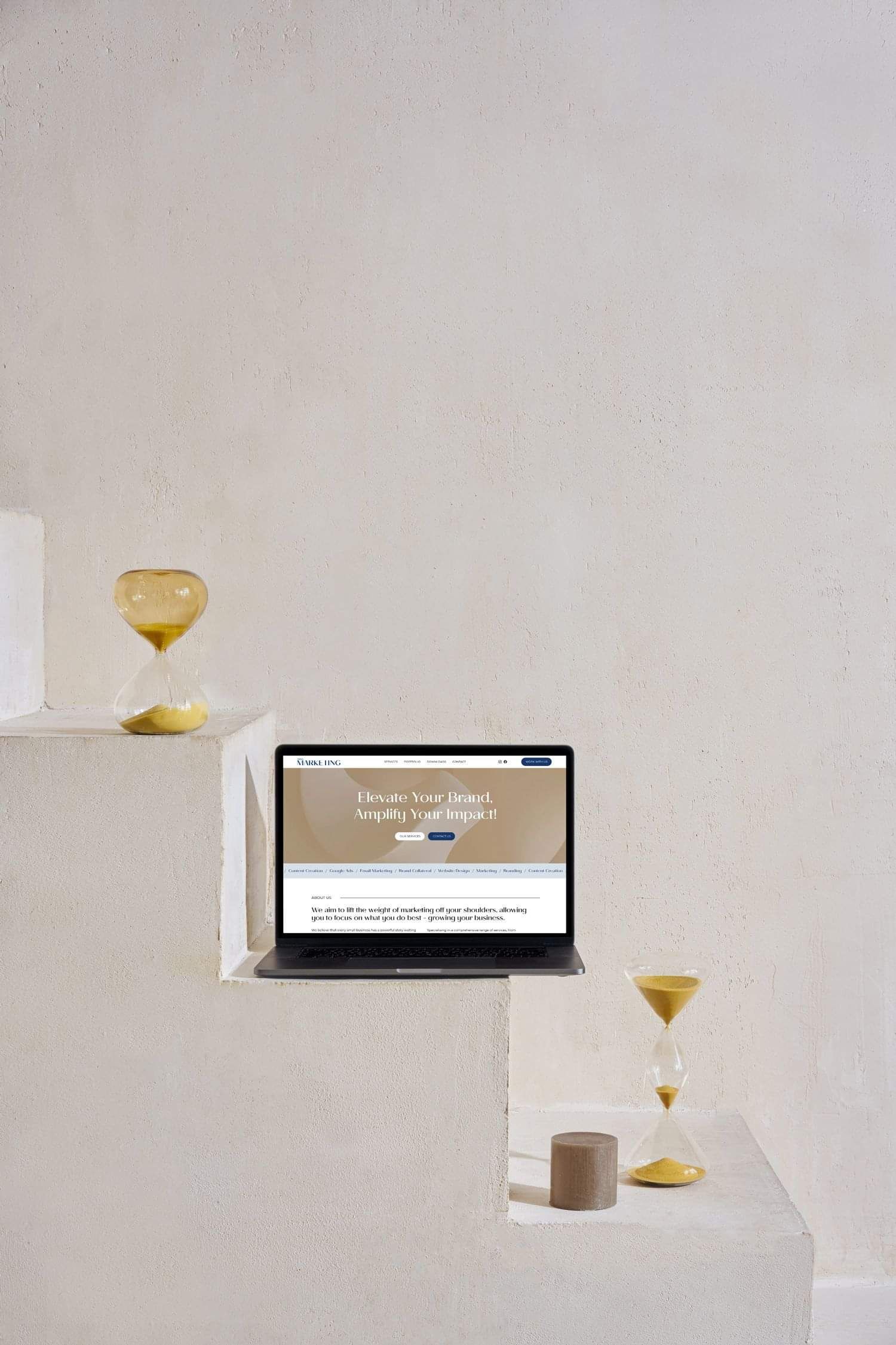 A laptop displaying the homepage of a website on a white background with a yellow hourglass, symbolising timely web design services.