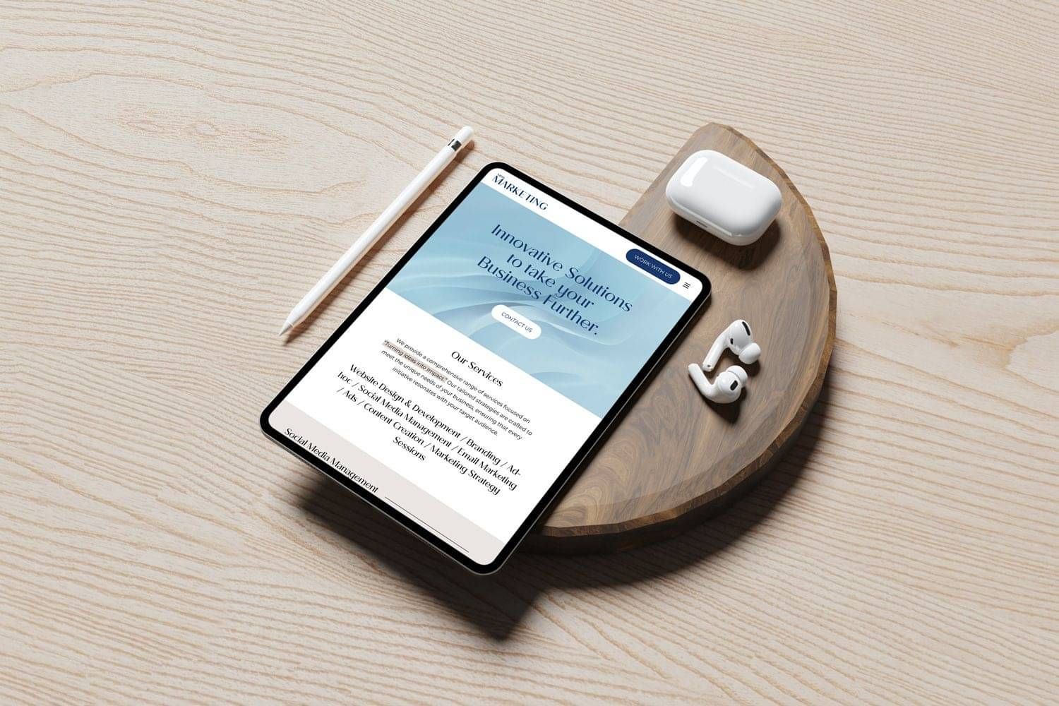 A tablet displaying a 'Our Services' page mockup, positioned on a wooden tray alongside a white stylus, AirPods, and a charging case.