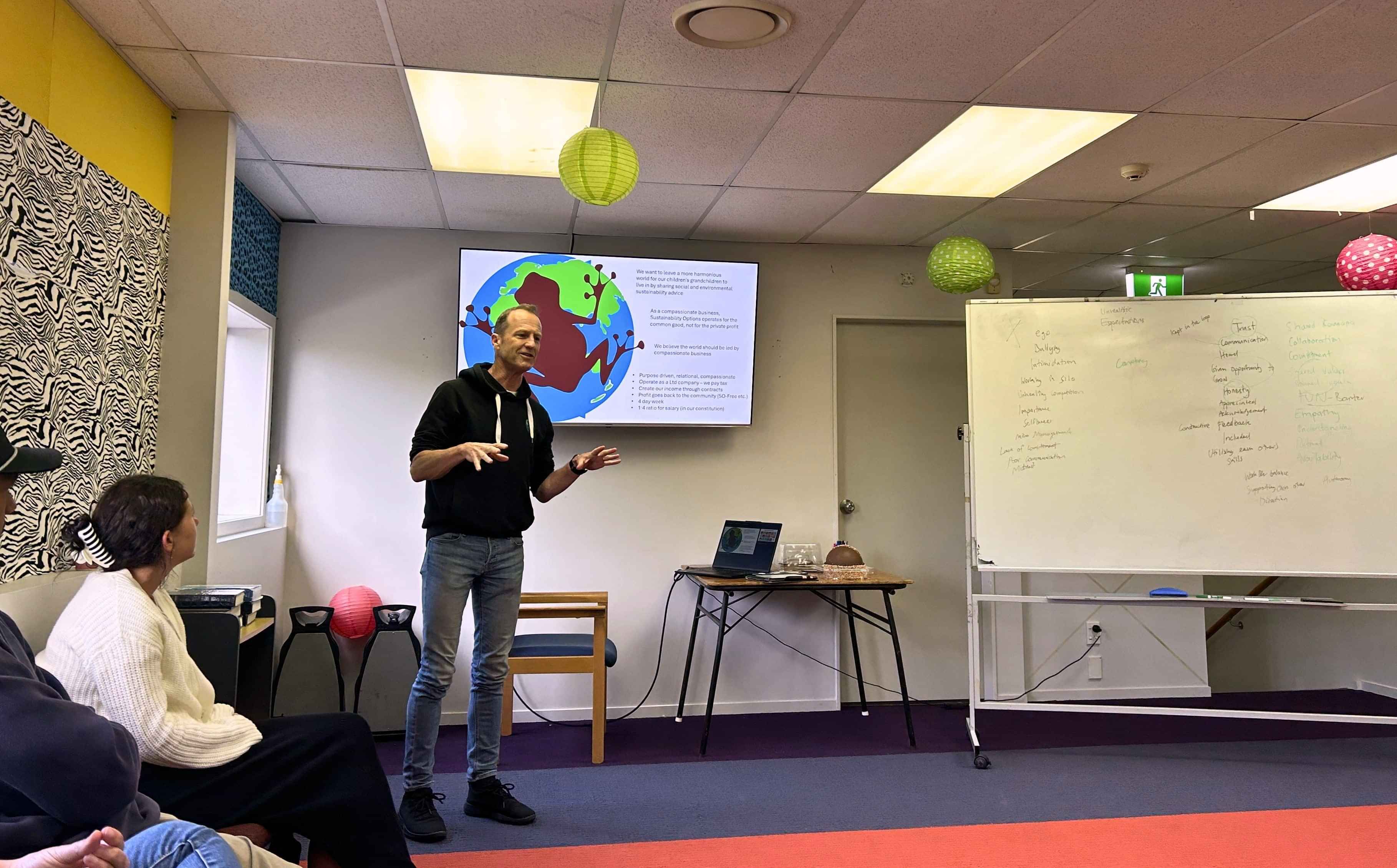 Presenter leading a workshop session in a meeting room with attendees seated and listening